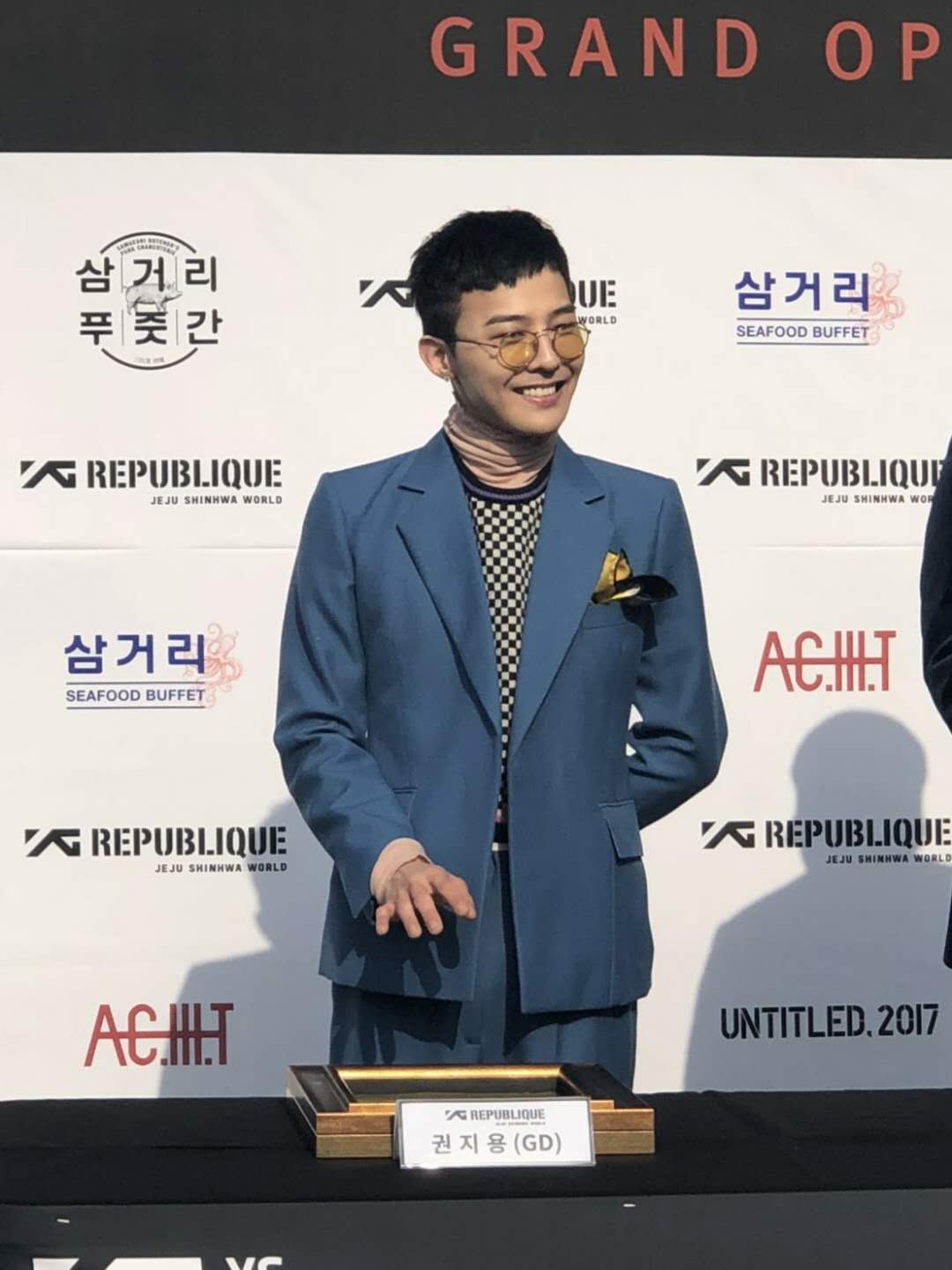 G-Dragon昨（25日）為他所策劃的GD咖啡廳與保齡音樂吧正式揭幕，秀出入伍前的小平頭，滿面笑容看出好心情。（領袖公關提供）