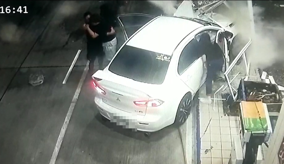 驚險一瞬間,白色三菱轎車高速衝撞加油站,由於車輛漏油冒煙,加油員工趕緊將陳姓男駕駛以及楊女乘客拉出來。(警消提供)