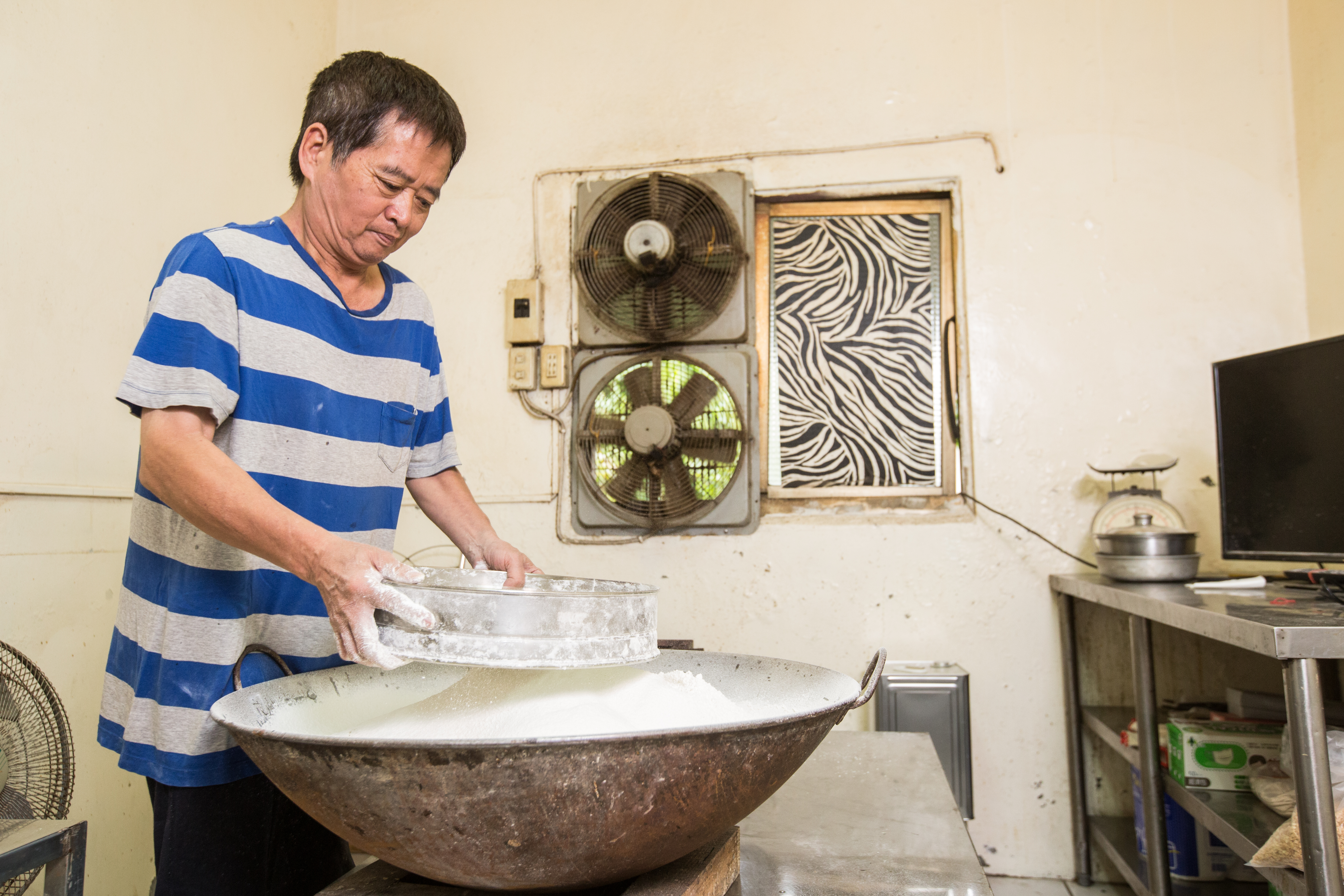 母親過世後，楊仁彬歷經2個多月實驗，才成功調製出粉漿比例，煎餅口感比昔日更加香脆。圖為將麵粉過篩。