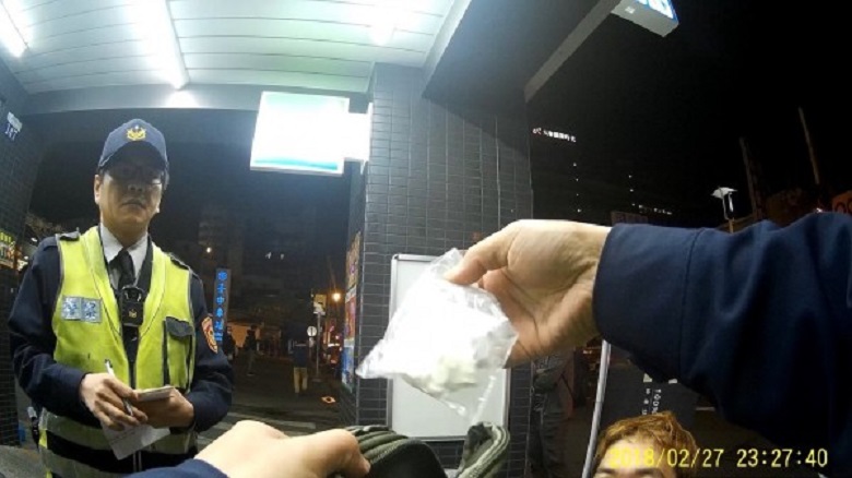 警方在他腳邊的塑膠袋搜出一小塊海洛因與FM2藥丸。（警方提供）