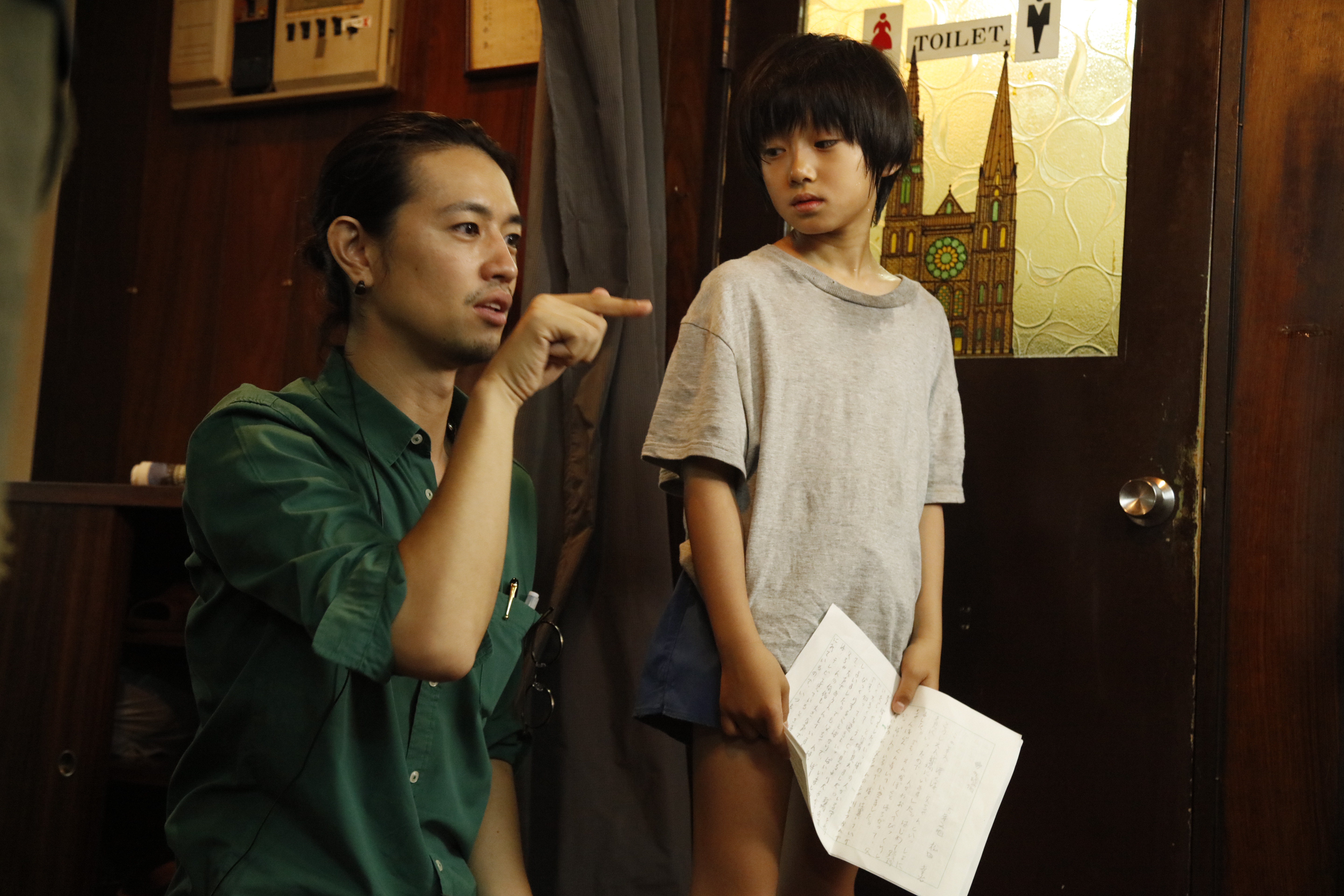 齊藤工（左）指導小童星大西利空表演《多桑不在家》裡手拿得獎作文給父親看的戲。（天馬行空提供）