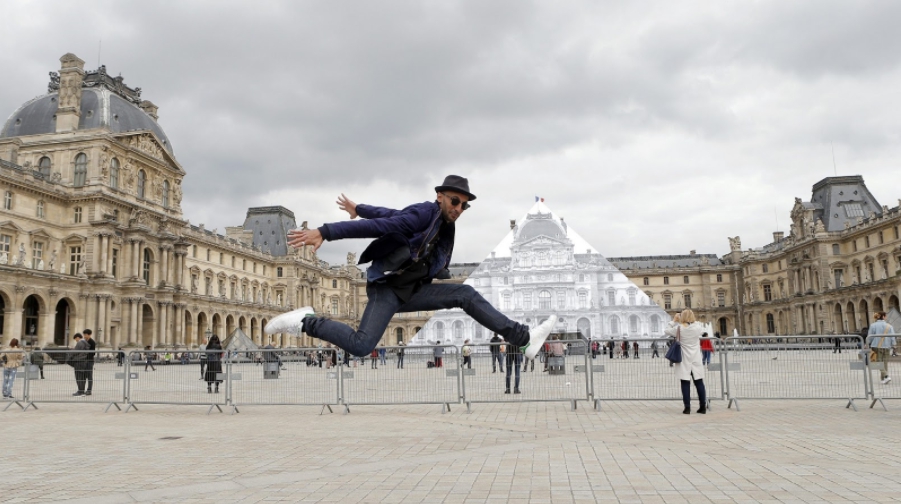 JR把700張海報拼成21公尺高的羅浮宮照片，包覆住廣場上的金字塔外觀，從特地角度看過去像把金字塔「隱形」了。（海鵬影業提供）