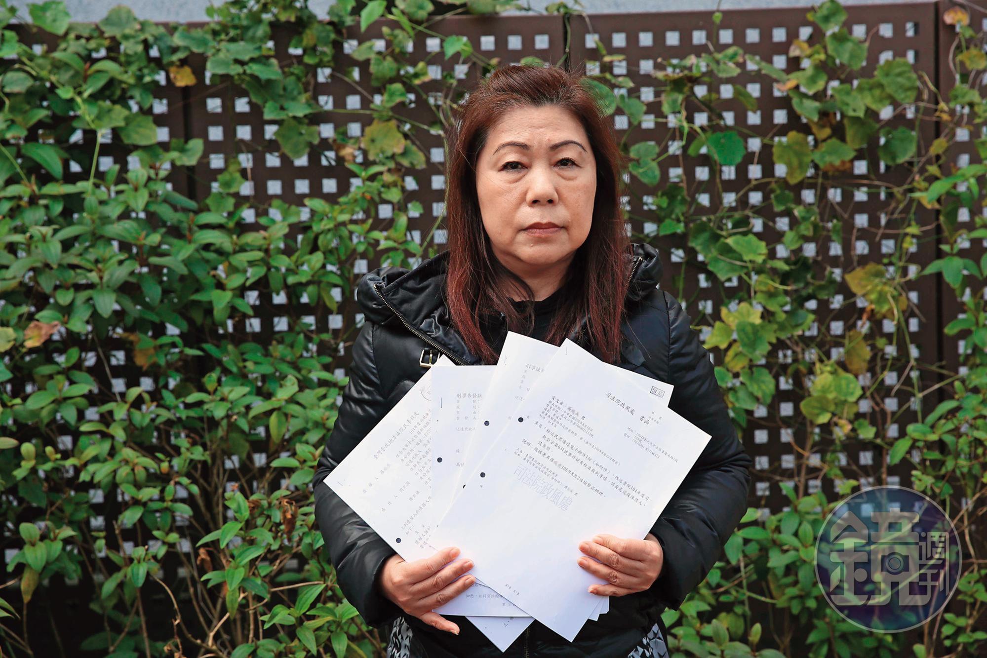羅女拿著含檢舉函在內的法院文書,控訴司法不公。