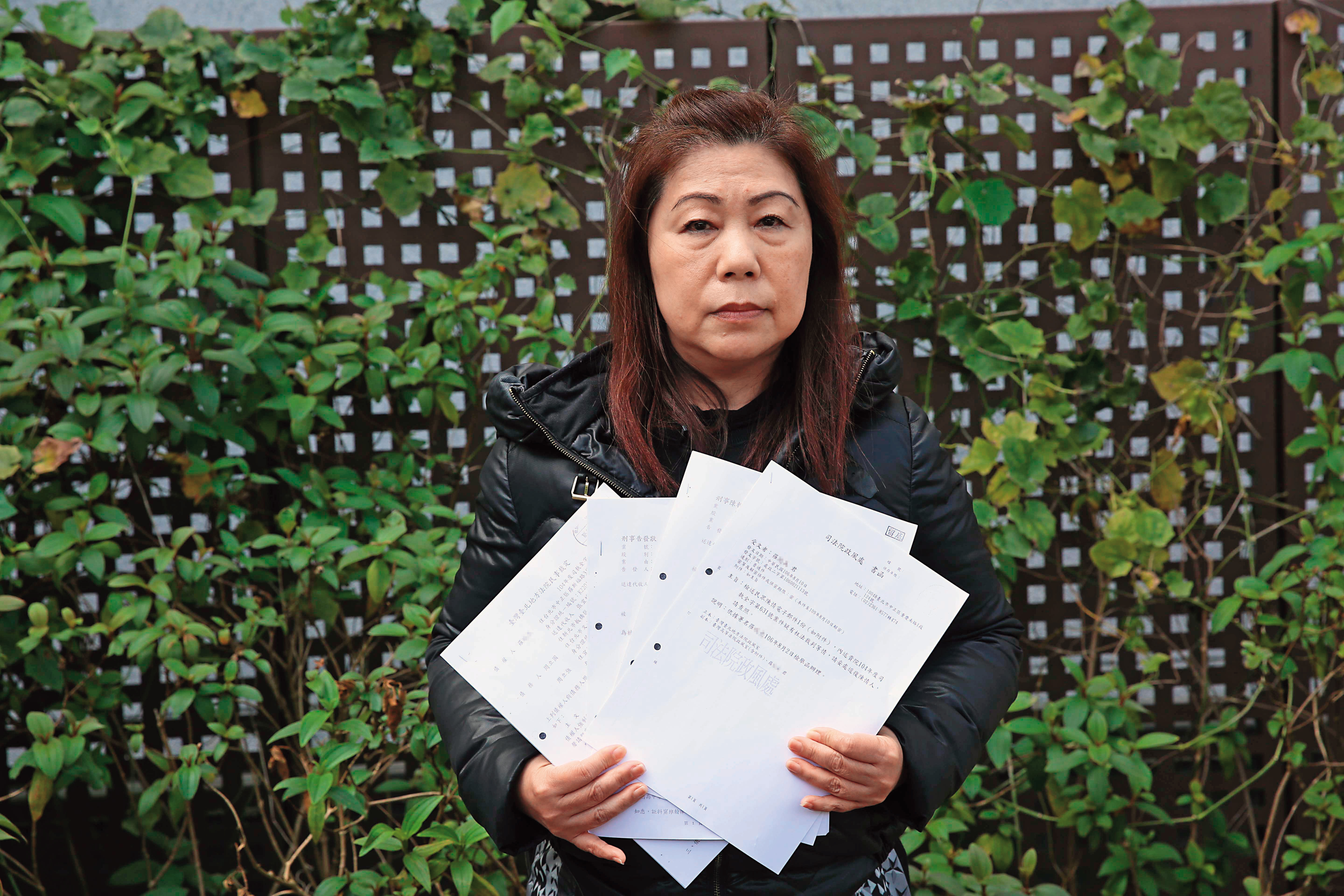 羅女拿著含檢舉函在內的法院文書，控訴司法不公。
