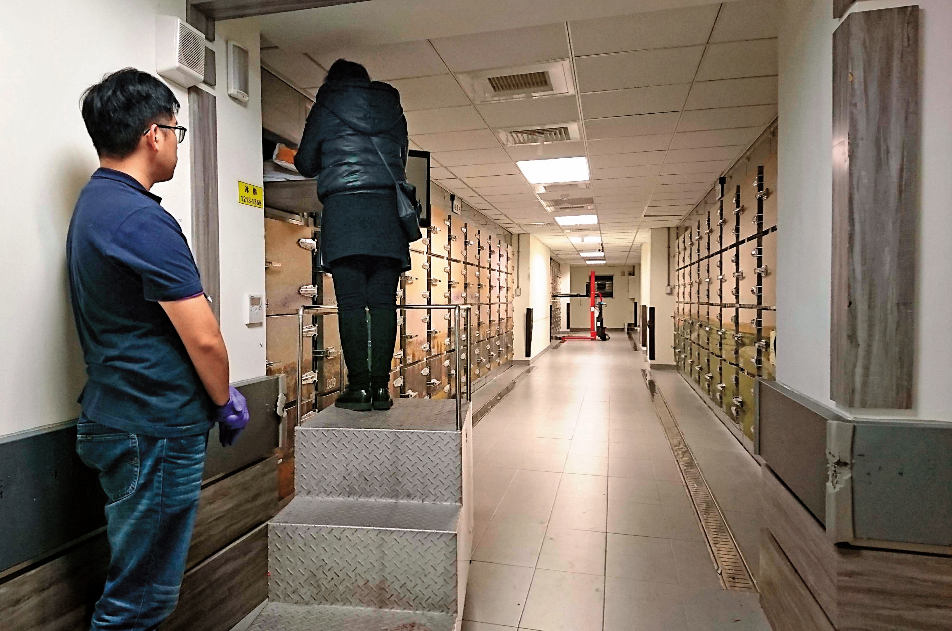 羅女看著冰櫃中已經發黑的丈夫遺體，泣訴和繼子撕破臉的情形。