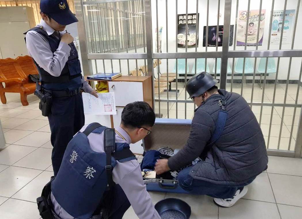 汪男即使進警局還是不將鋼盔脫下，隨身攜帶的行李箱則裝有個人衣物和筆電。