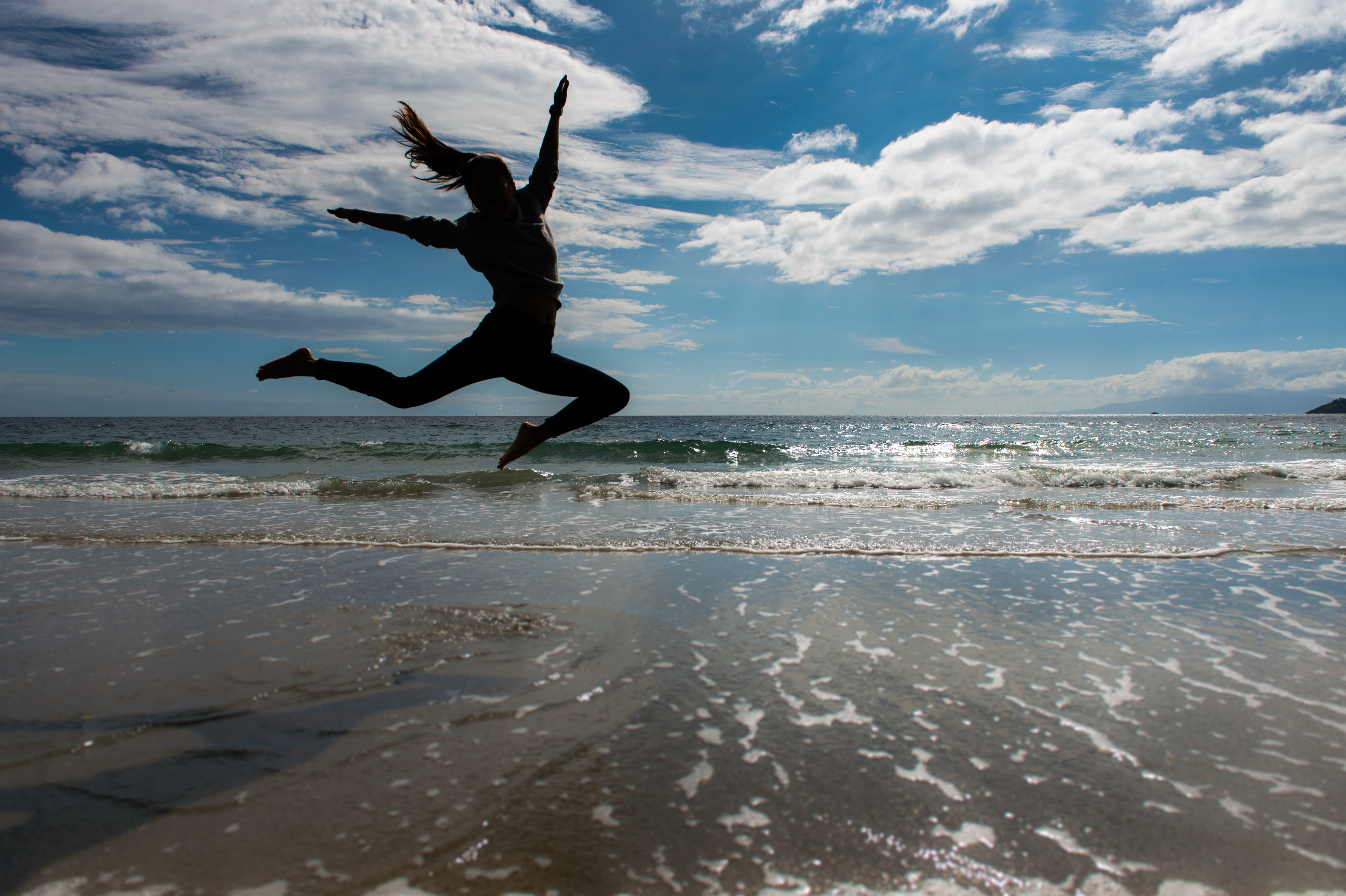 旅人跳躍海灘，奔放快活的剪影，說明了紐西蘭的無拘無束。