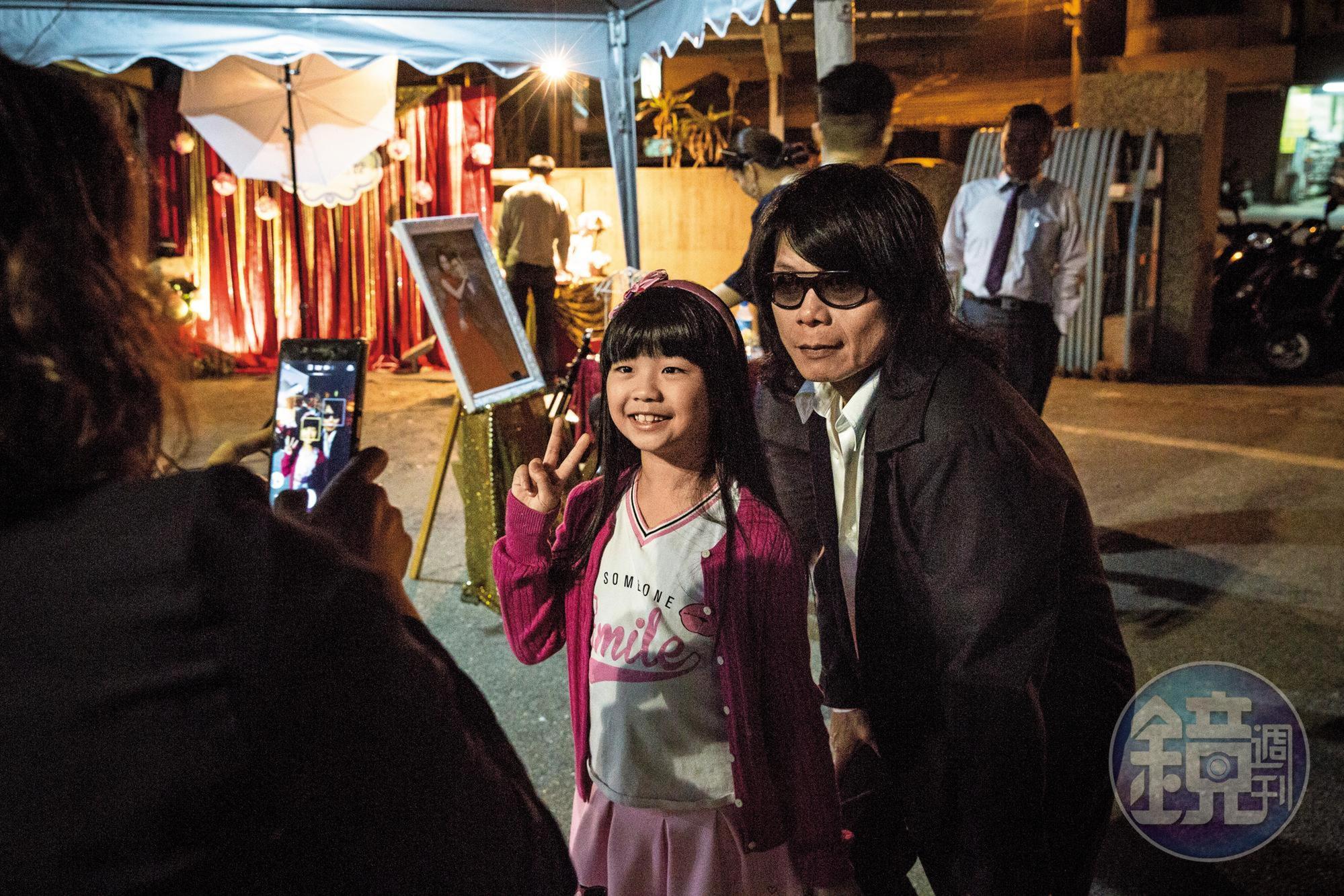 月華光(右)接下婚宴演出,站在台邊看前輩演奏,有賓客帶著女兒前來歡喜合照。