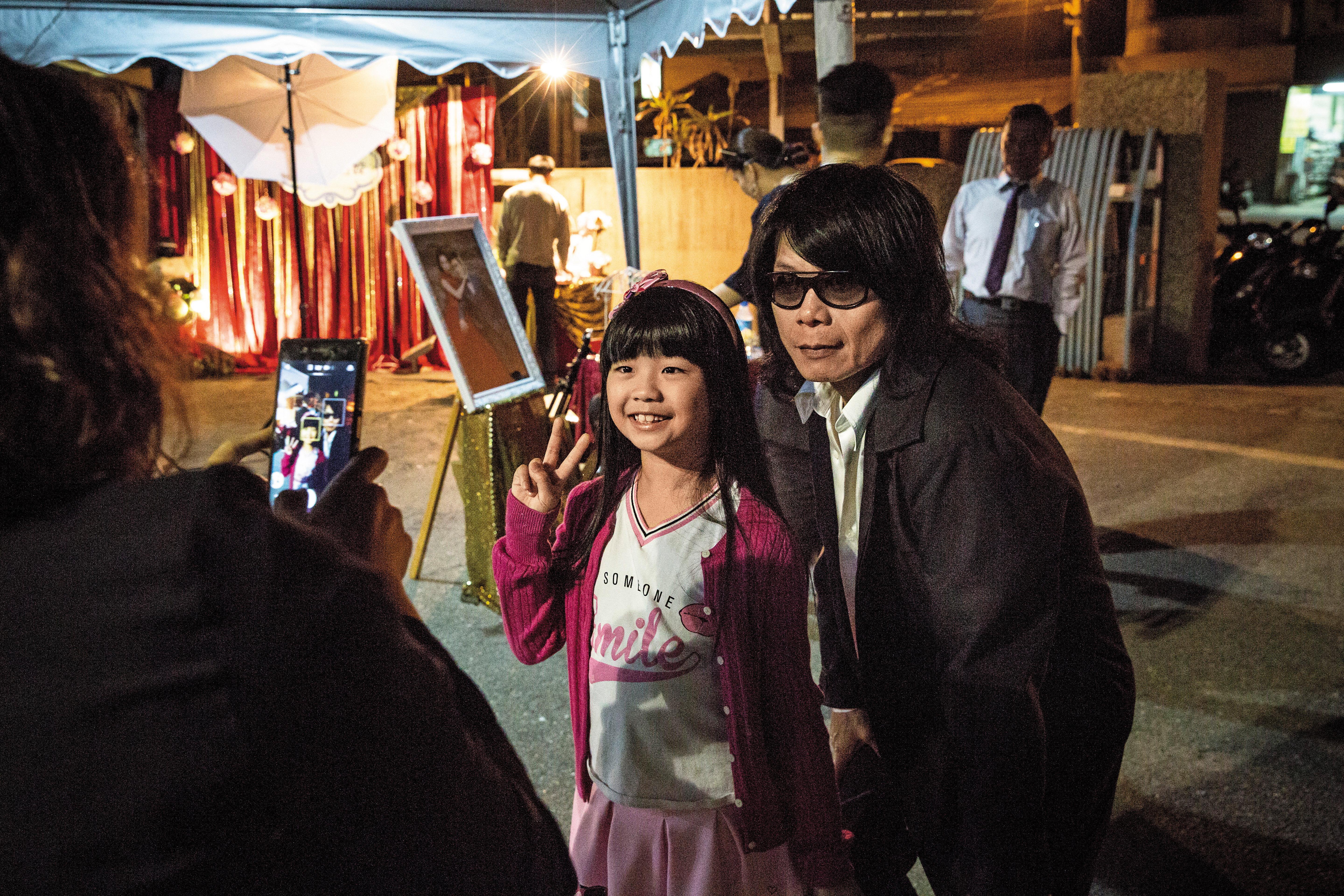 月華光（右）接下婚宴演出，站在台邊看前輩演奏，有賓客帶著女兒前來歡喜合照。