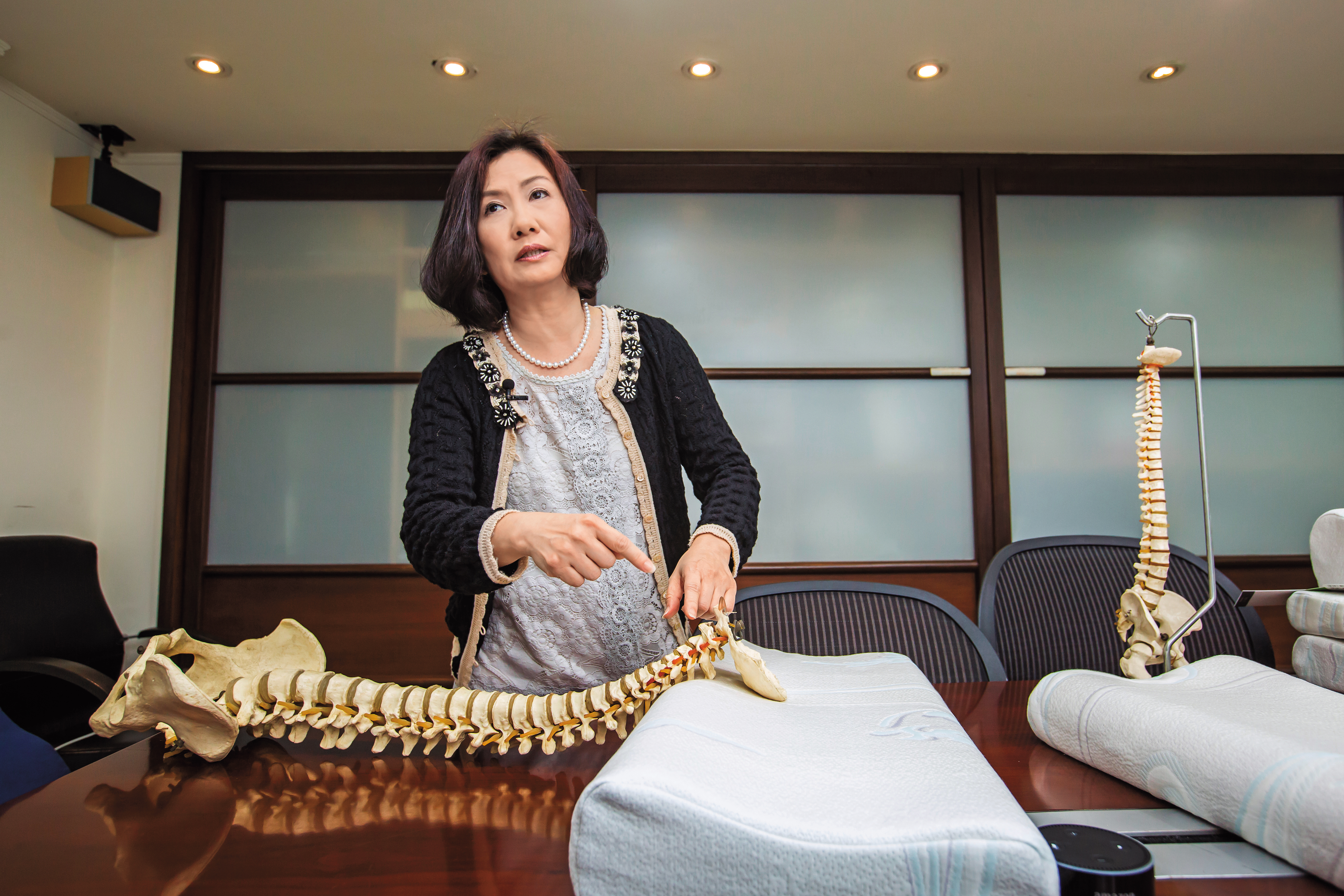 譚芙芩利用人體脊椎模型，在裸枕上調整示範正確頸枕睡眠姿勢。