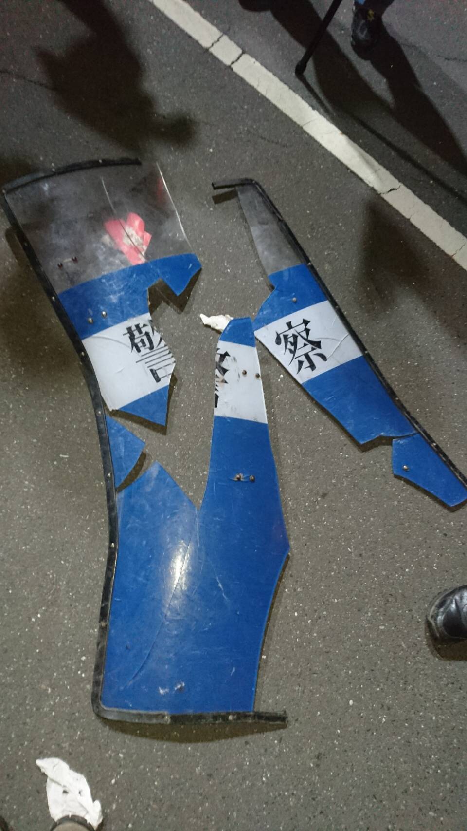 遭到反年改團體攻擊後的警用盾牌碎裂一地,被網友笑稱:「這是紙糊的嗎?」(翻攝畫面)