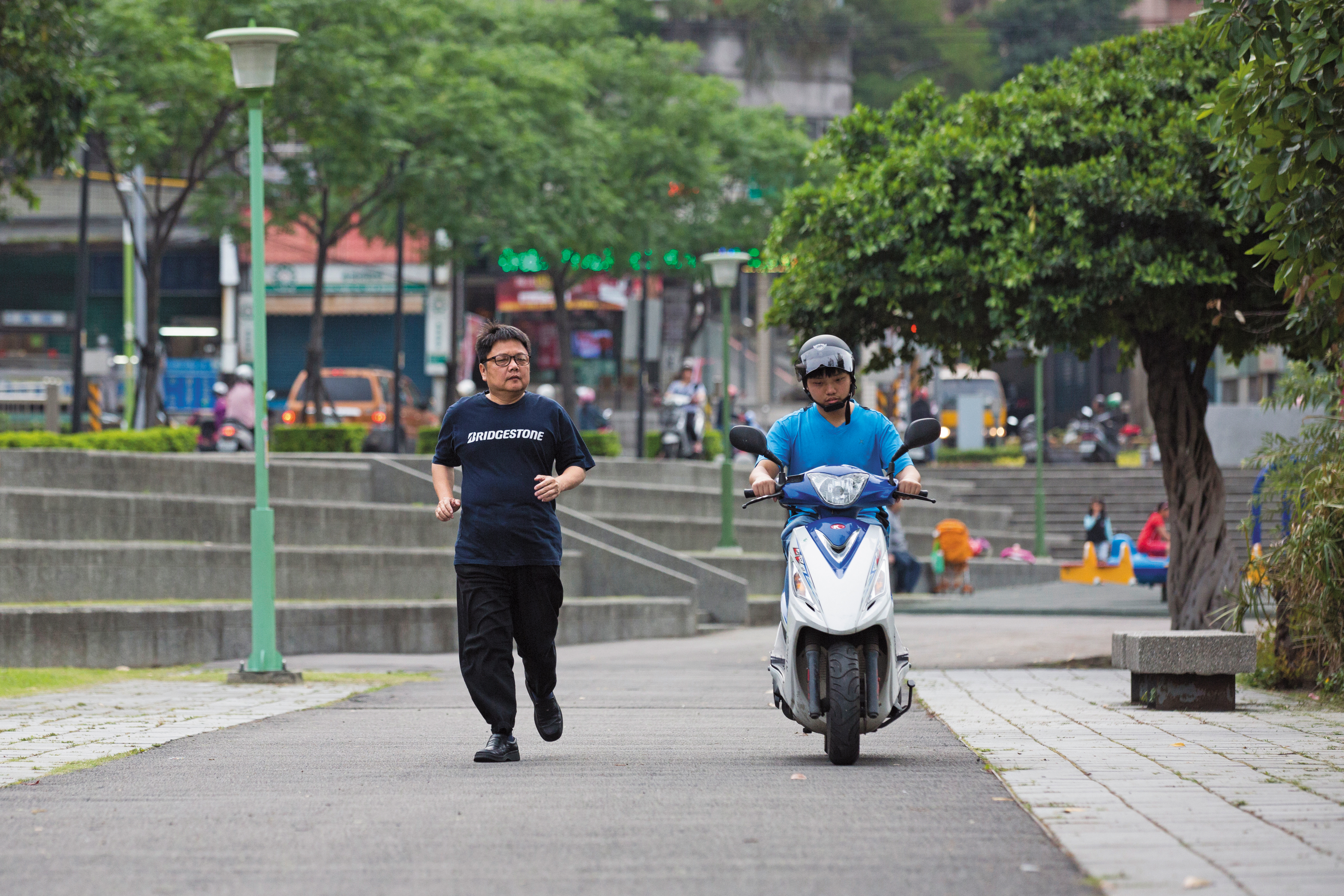 張伯榮(右)除了自閉症,也有學習遲緩的情況。這天爸爸(左)陪他到公園練習騎機車,準備考駕照。