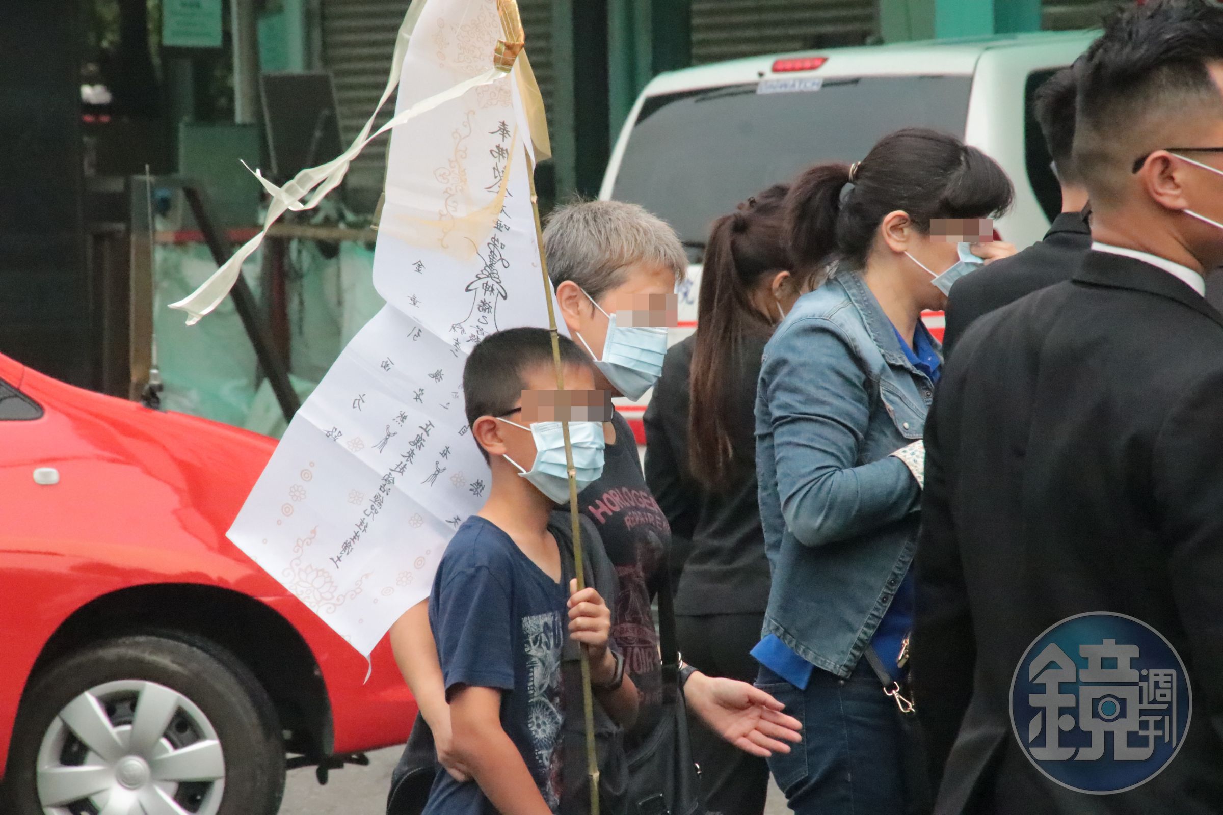 招魂隊伍中還有稚齡的孩童舉著父親相片，卻不清楚發生了什麼事情。