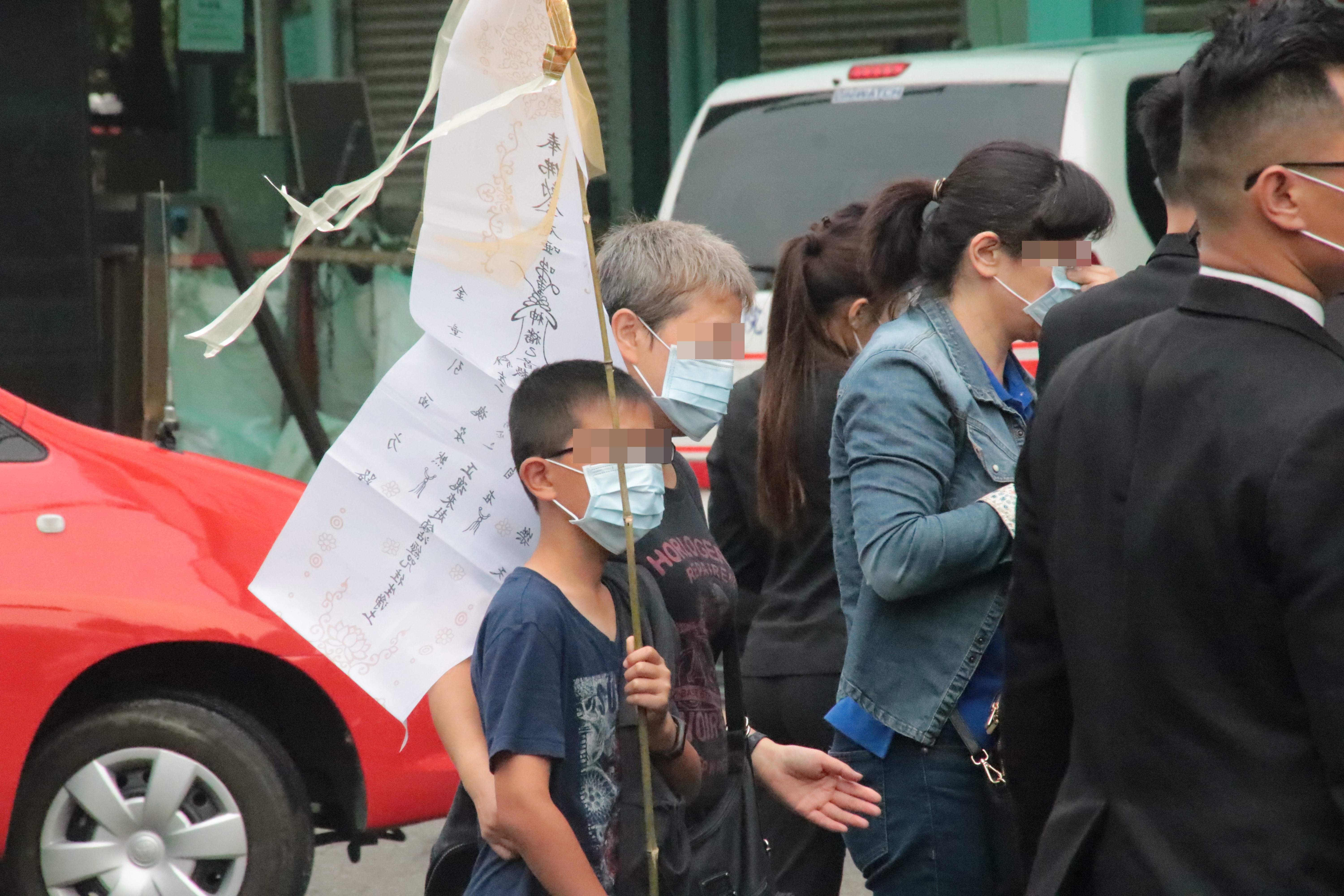 招魂隊伍中還有稚齡的孩童舉著父親相片，卻不清楚發生了什麼事情。