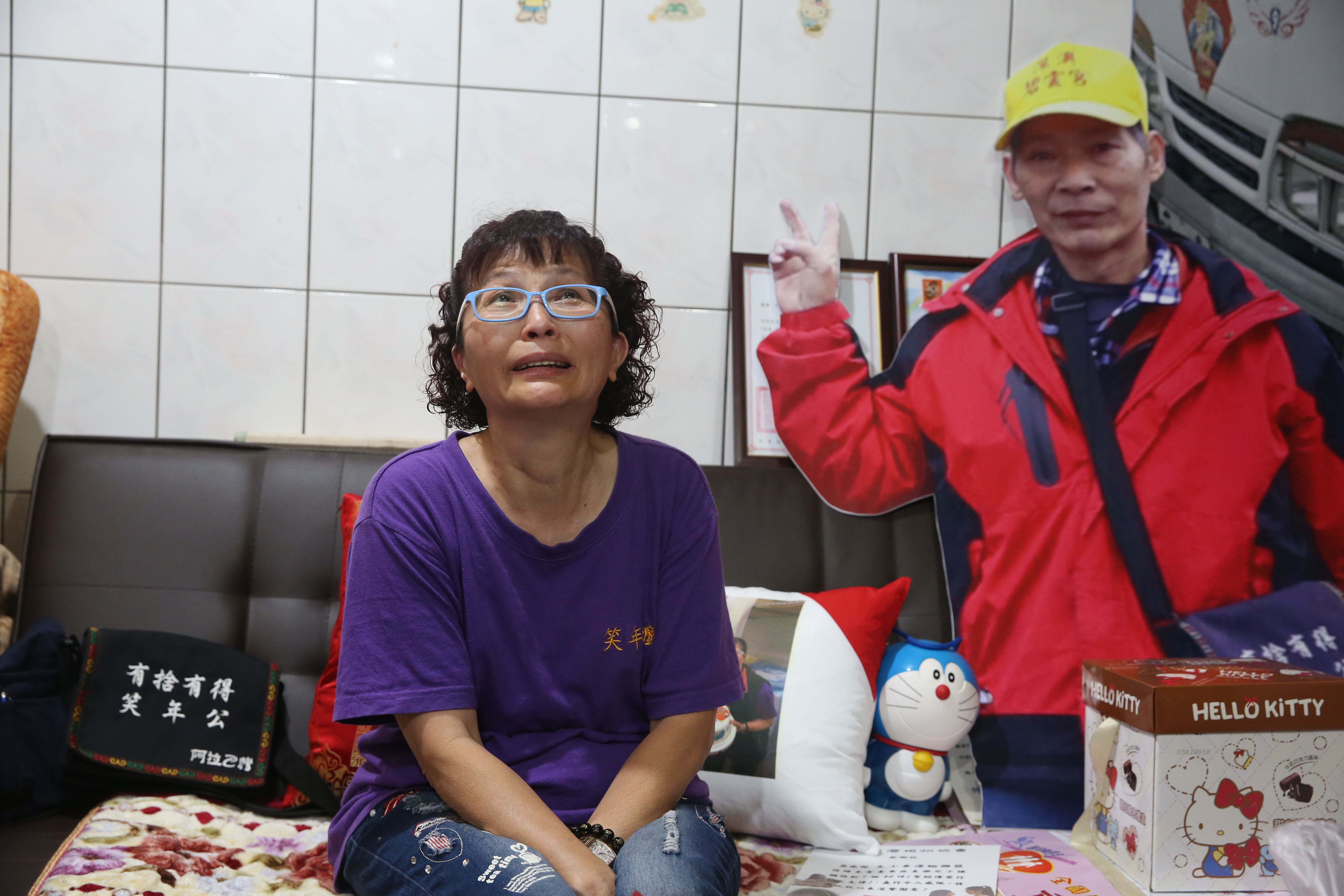 本名陳素玲的「笑年嬤」提起過世的老公還是忍不住流淚，她最近帶著老公的人形立牌環島旅行，回家後，立牌就放在老公生前睡的沙發上。