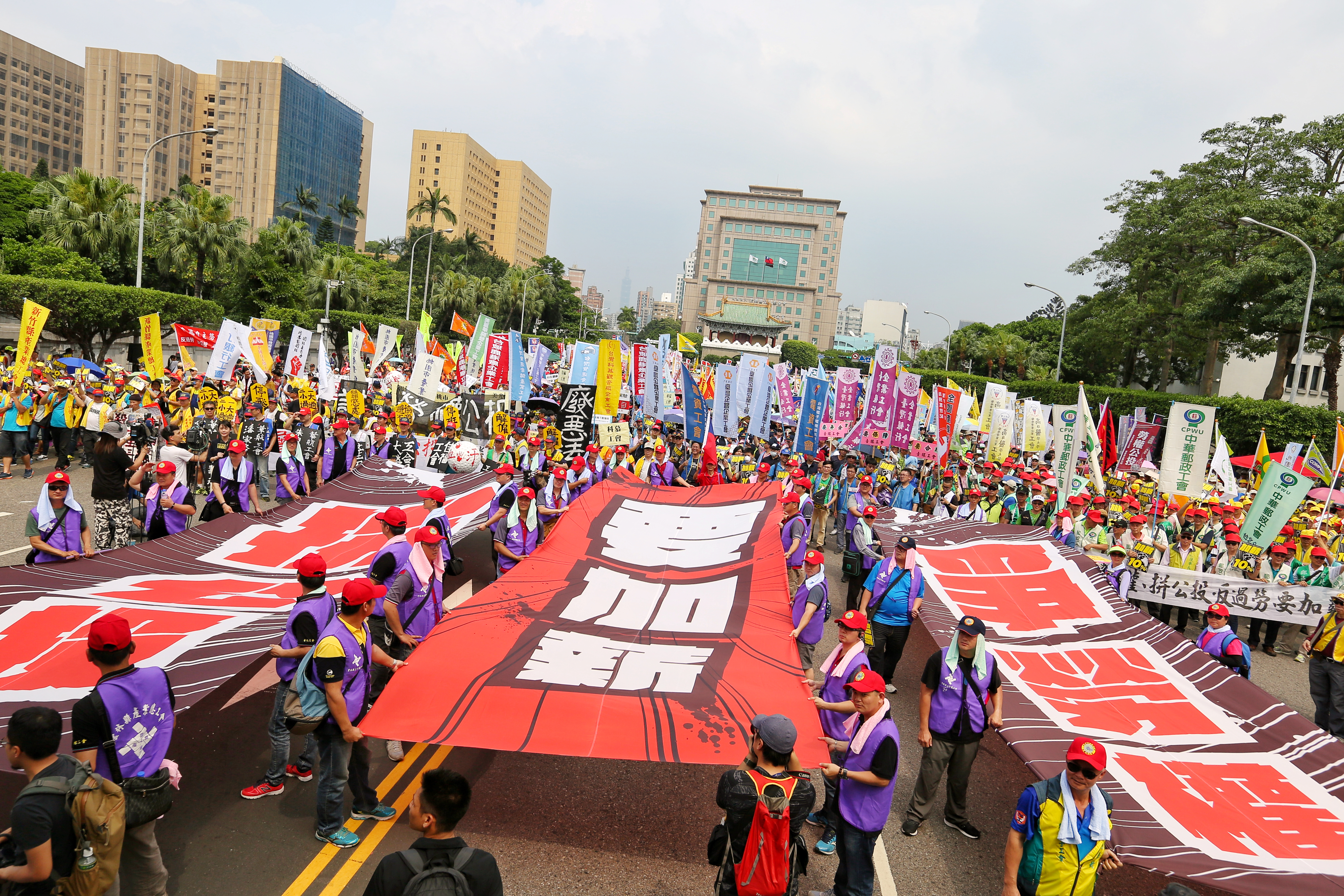五一行動聯盟在遊行隊伍前方高舉「要加薪」等巨幅布條表達訴求。