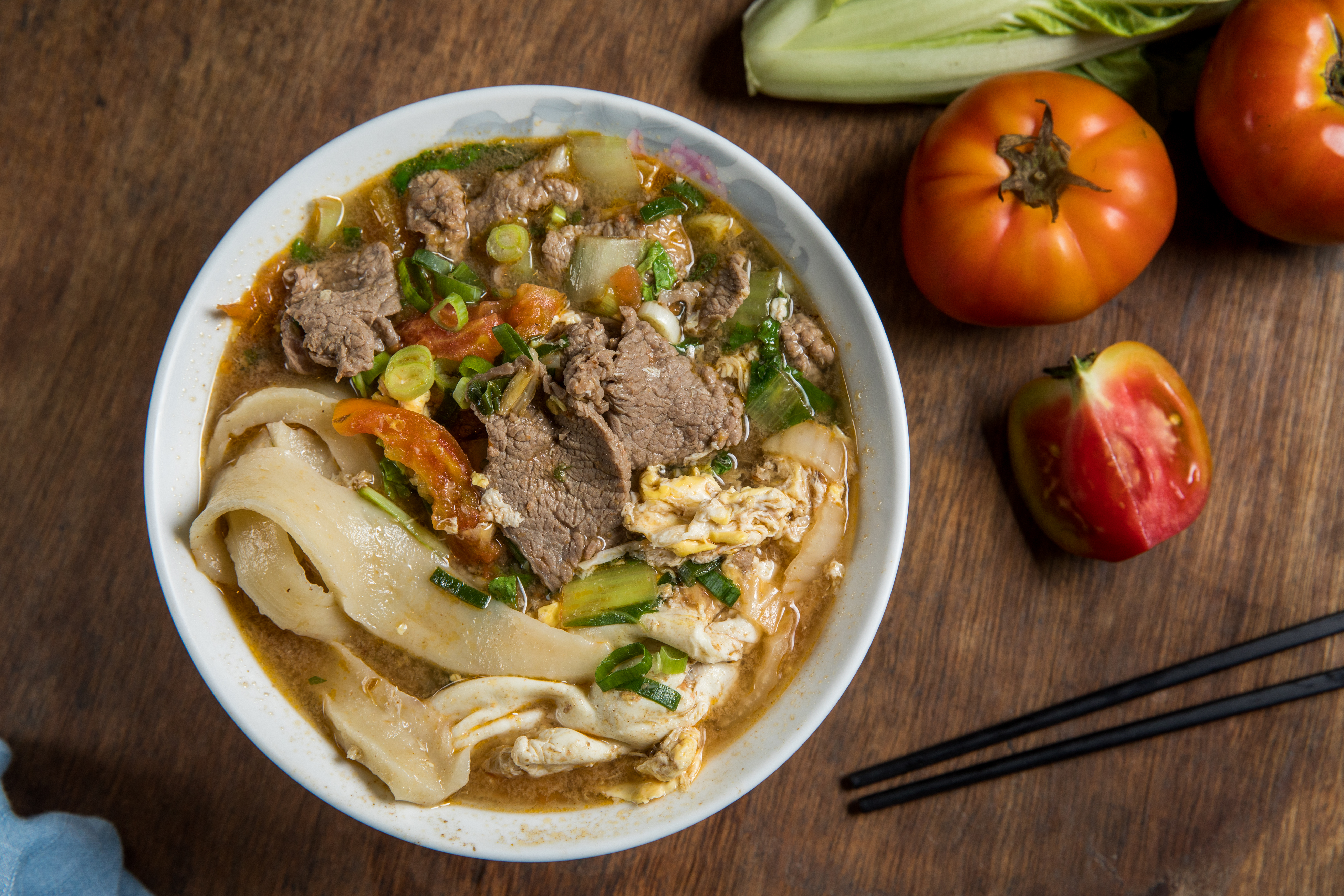 「番茄煮牛肉麵」的湯底用牛骨、洋蔥熬出自然甘甜，配料像小火鍋般豐盛。（110元／碗）