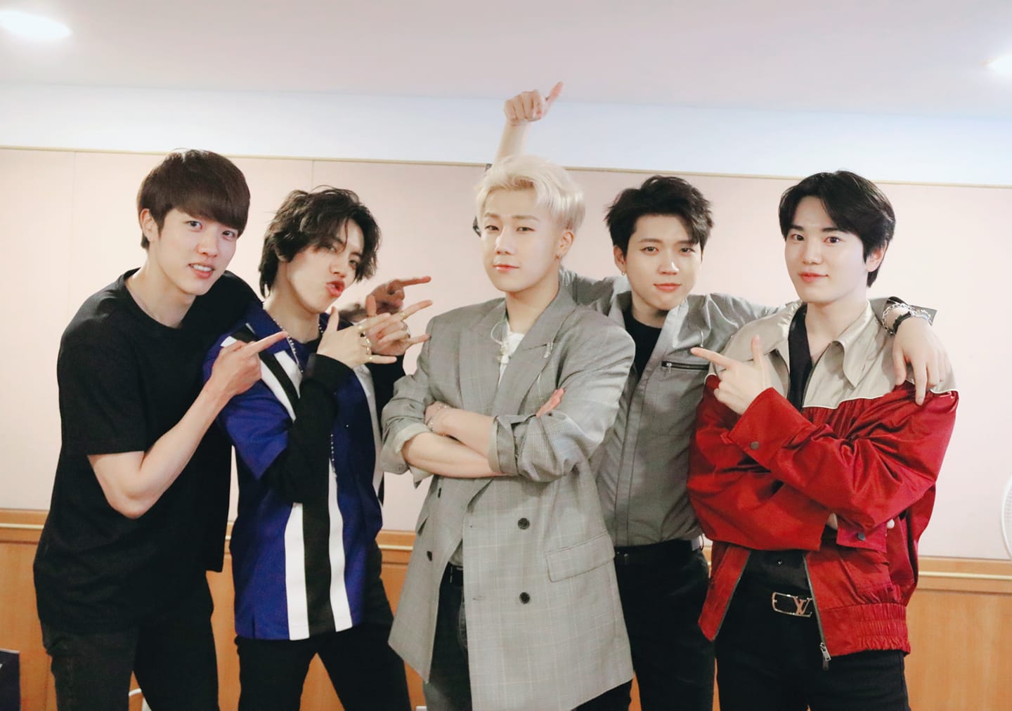 INFINITE隊長金聖圭（中）在個人演唱會上宣布下週入伍，成員在後台與他合照。（翻攝自INFINITE FB）