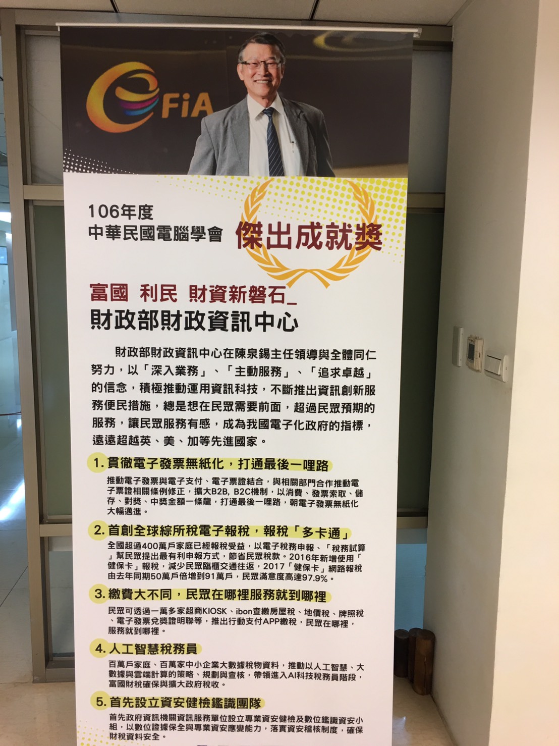 陳泉錫主任的人形立牌,放置於財資中心顯眼處,上面詳列5大政績。