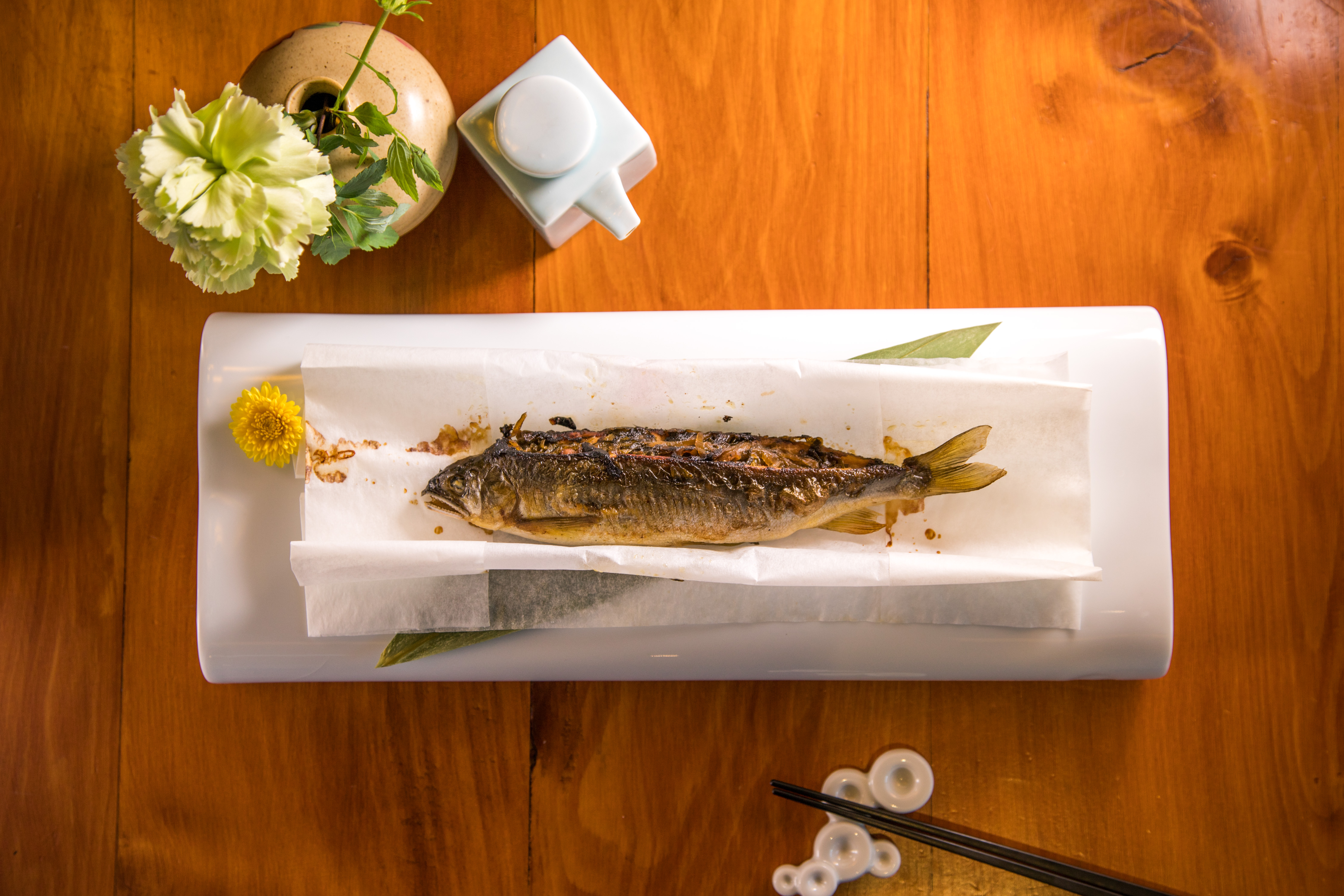 展開卷紙，「酸菜香魚」擺盤如日式料理，抱卵的香魚和酸菜，蘸著壺底油入口，帶有台灣菜熟悉的醍醐味。