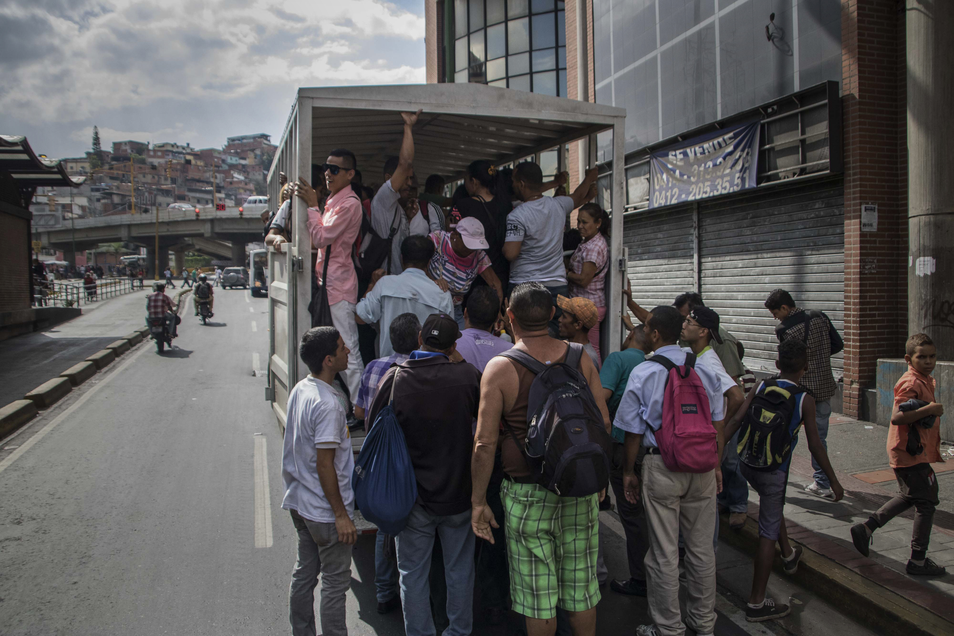 擁有全球最大原油儲備蘊藏量的委內瑞拉,曾是南美最富有的國家,如今卻陷入史上最嚴重的政治和通膨危機之中,圖為首都加拉加斯的民眾,試圖搭上被當作公共交通工具的貨車。(東方IC)