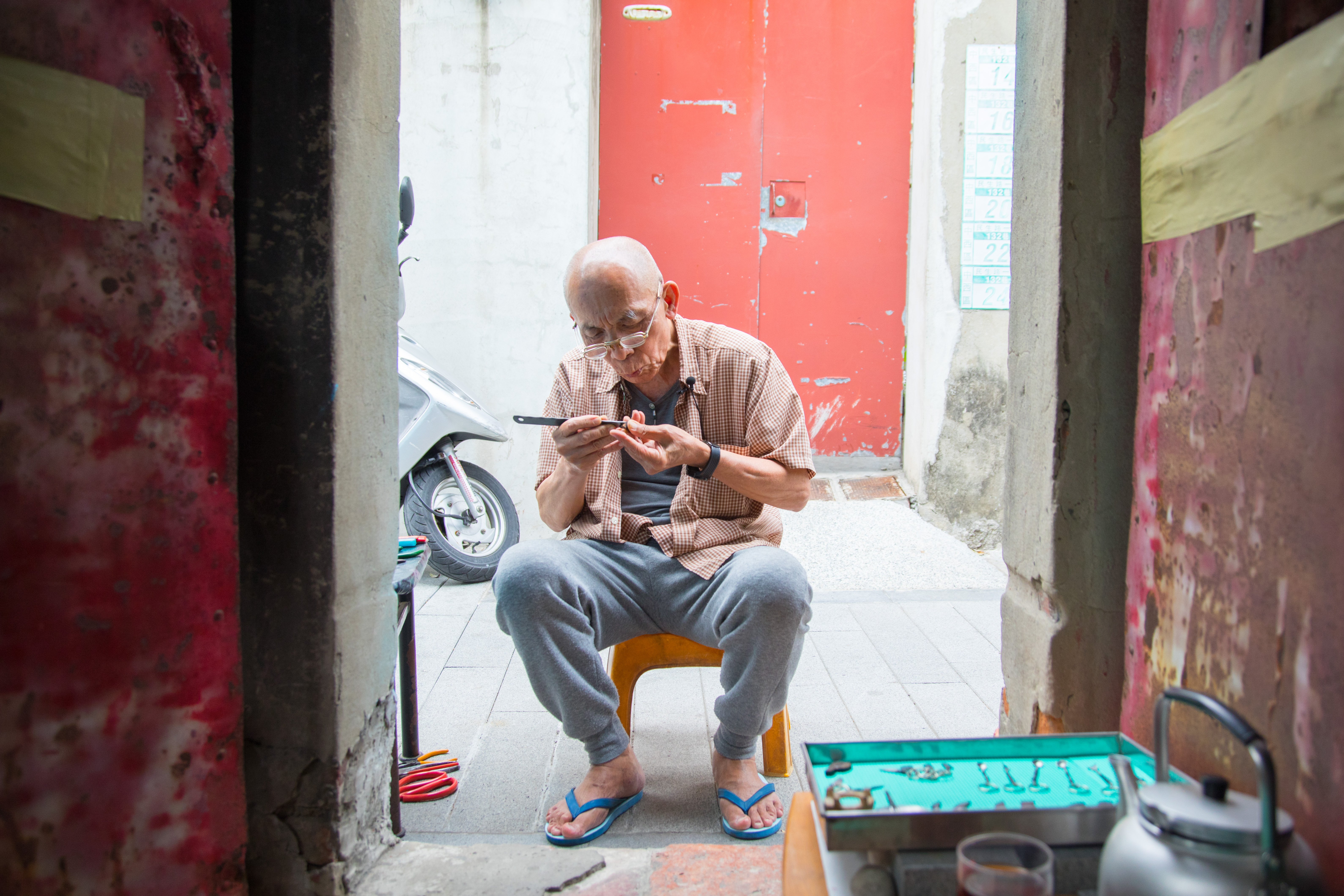 老得伯坐在家門口雕磨菜刀，雖然高齡78歲，創作動力不輸年輕人。