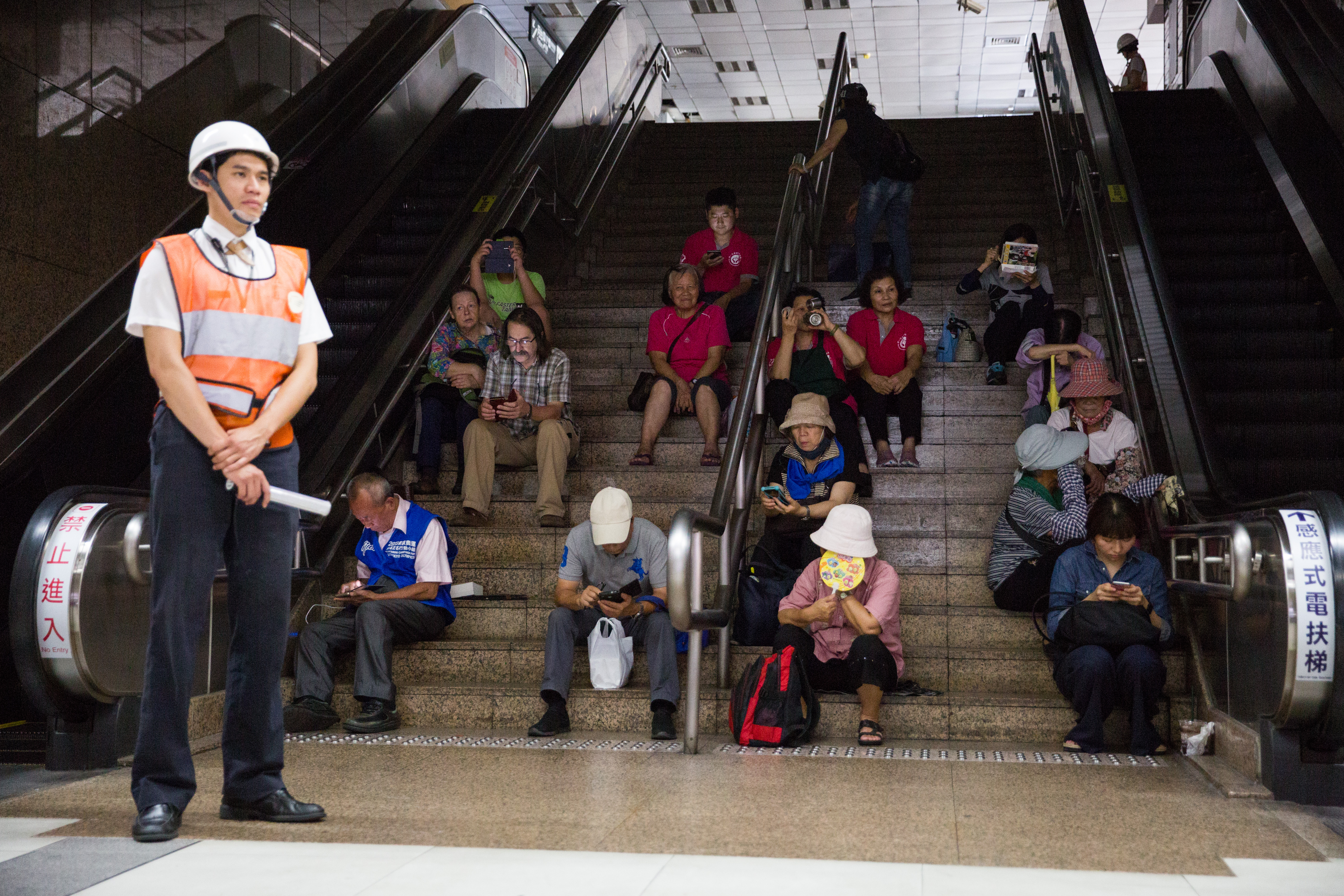 捷運站內旅客無法出站，枯坐在樓梯上等待演習結束。