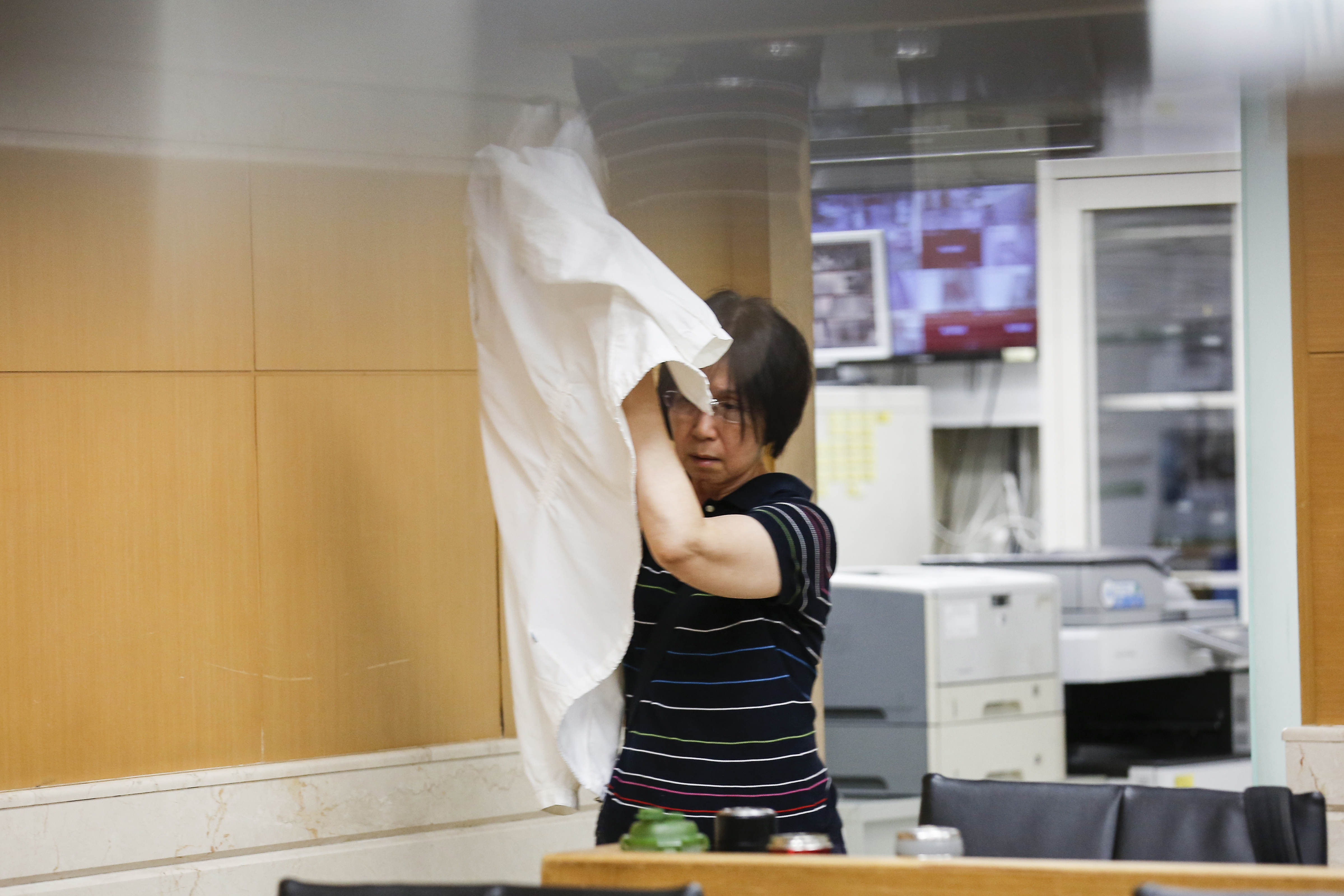 王永慶的謝姓外甥女涉炒股遭約談 ，見本刊採訪，立刻用外套遮臉。