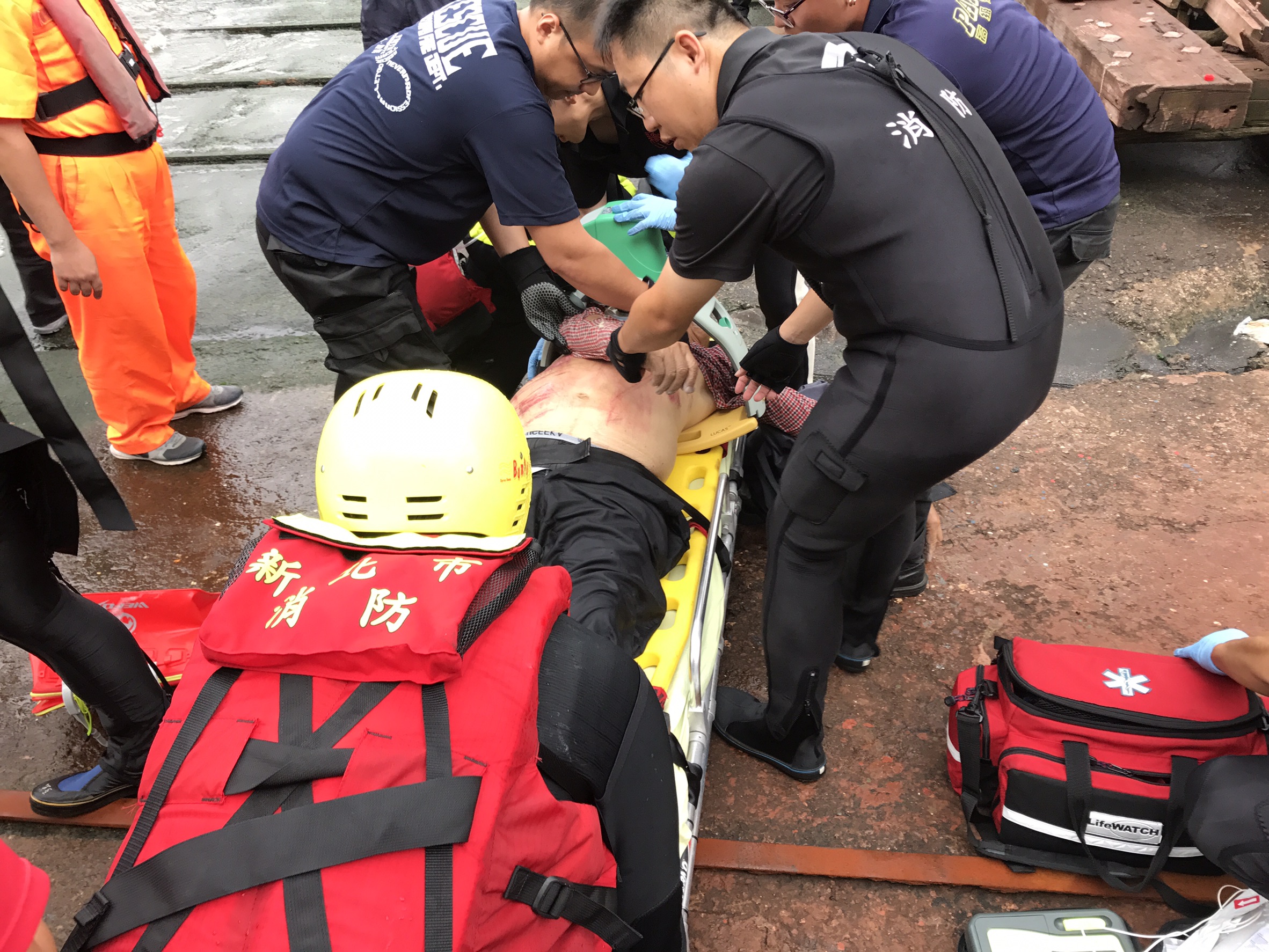 救難人員緊急將2人救起，但其中1名釣客失去生命跡象，救難人員現場為他急救。（翻攝畫面）