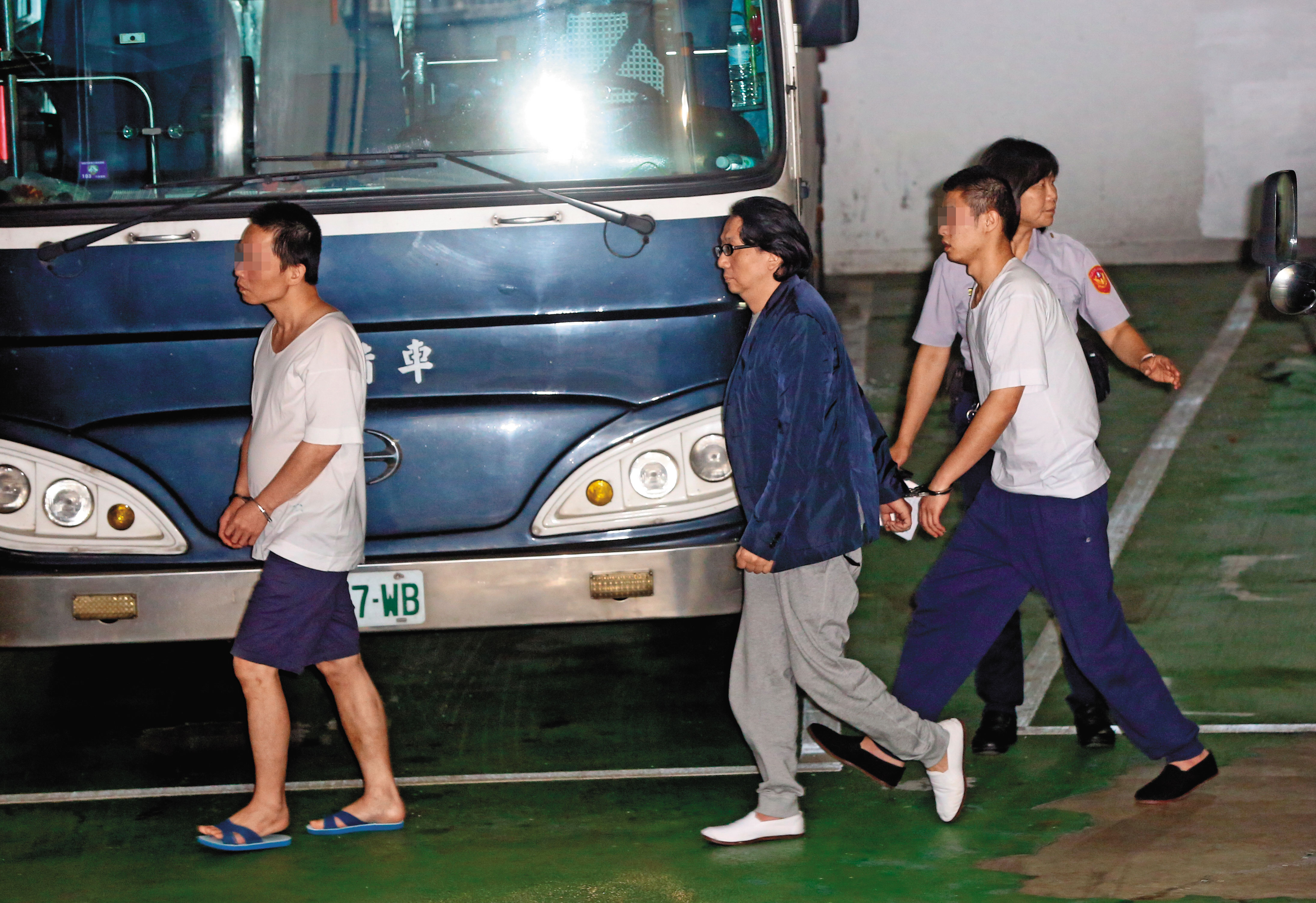 許金龍(左2)被收押長達年餘,日前遭法院提訊出庭,快步走下囚車,不發一語。