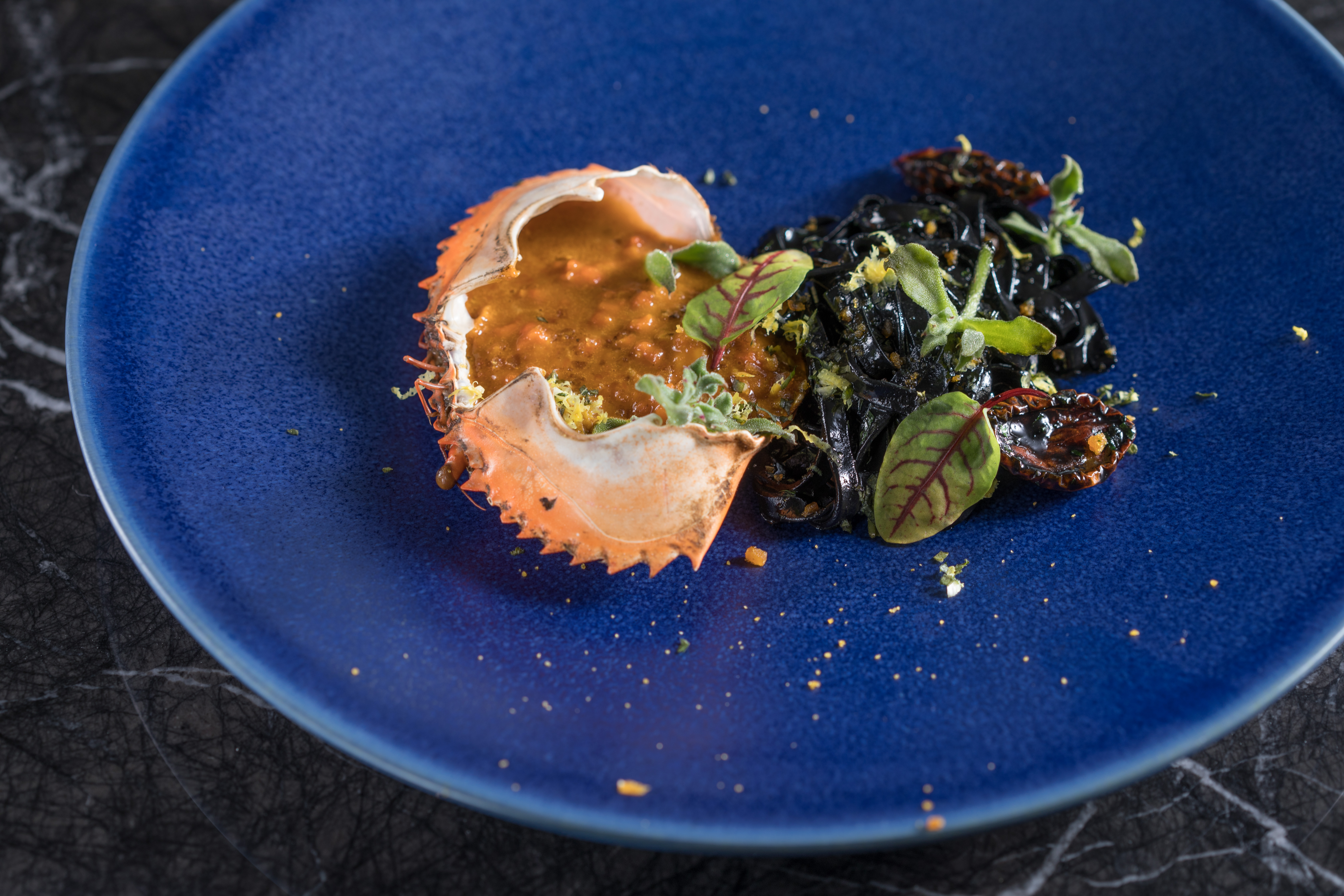 「手打墨魚烏冬・旬蟹・烏魚子」墨魚汁揉進麵條裡，煮麵條的湯底加入少許日式高湯，蟹殼裝進蟹肉、蟹膏，跟Q彈麵條拌著吃，洋溢鮮甜海味。