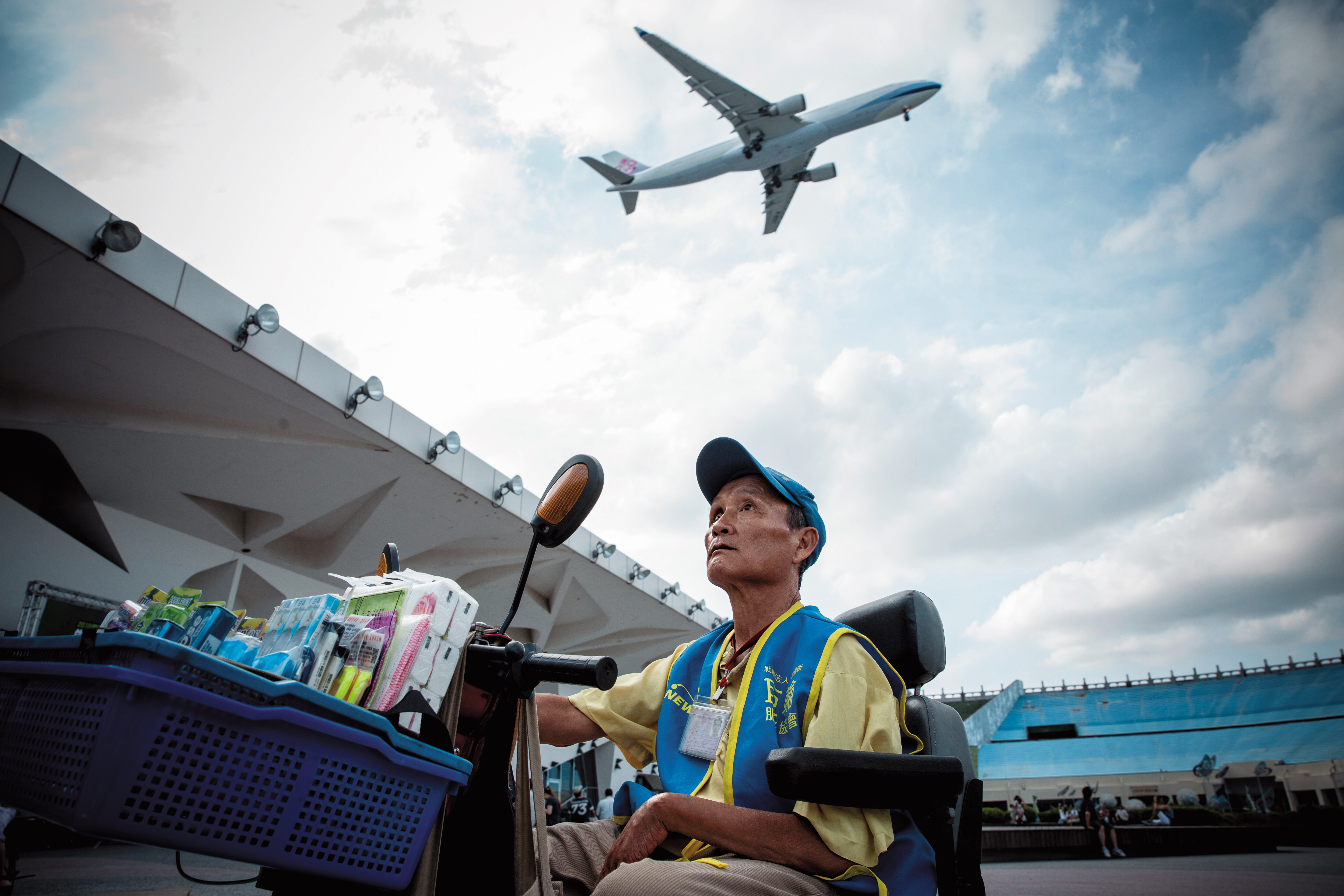 花博上空不時有飛機掠過，吳慶昇能去的地方並不多，要去的地方都是為了賺錢，他偶爾抬頭看一眼，接受命運將他困在地表的成為街賣者的事實。