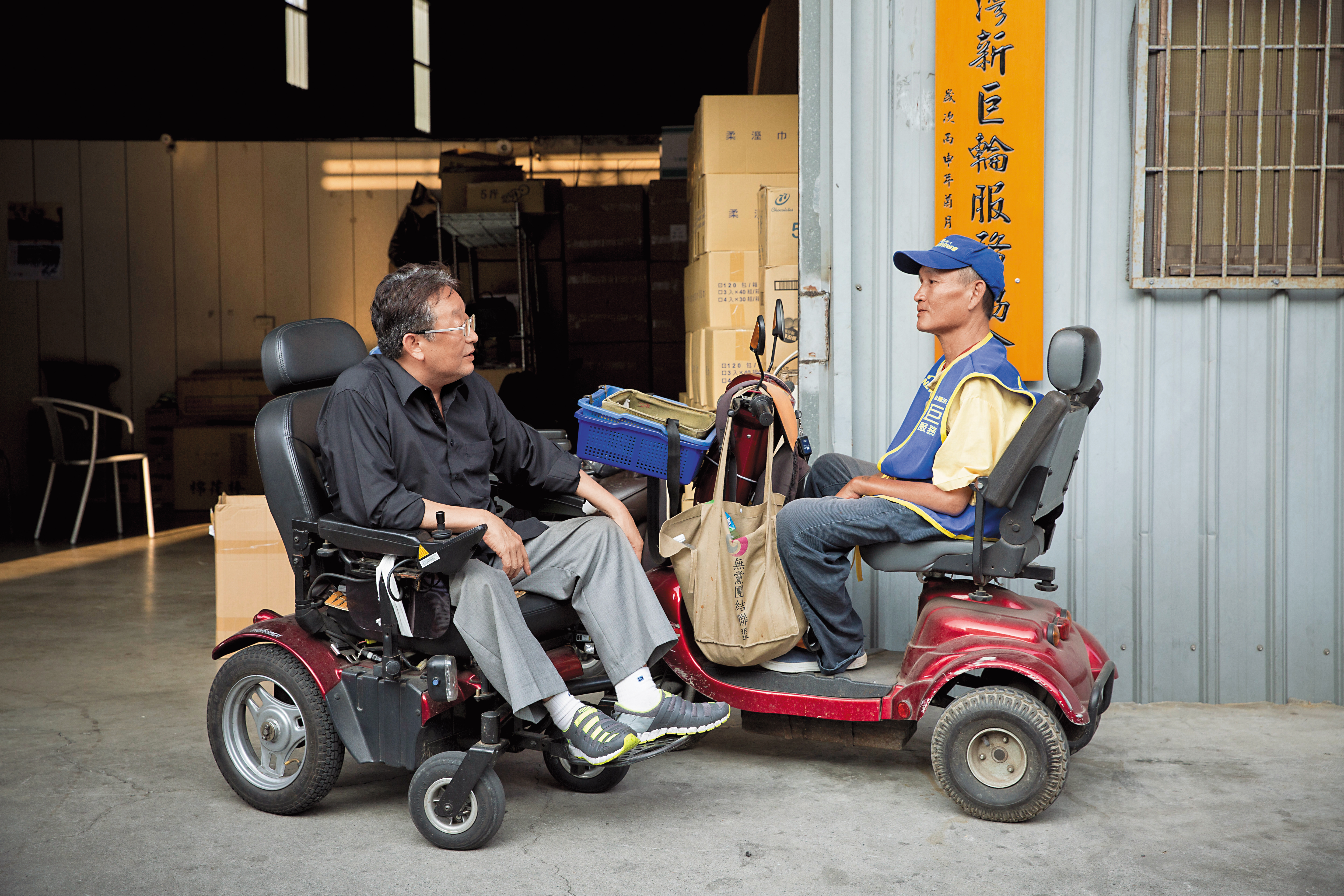 「社團法人台灣新巨輪服務協會」的匾額前，理事長陳安宗（左）和吳慶昇（右）聊家常。