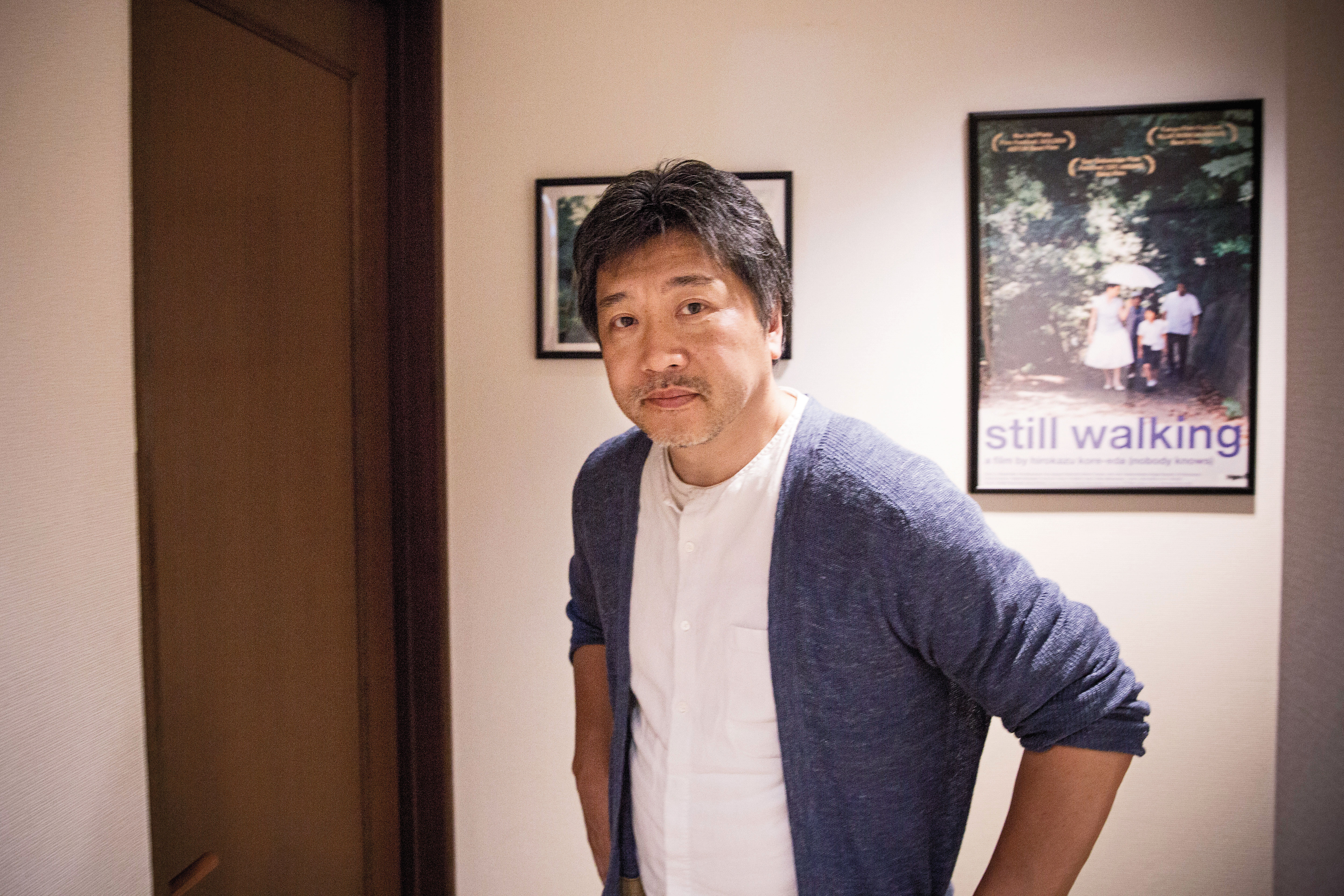 是枝裕和位在澀谷的工作室「分福」，走廊上掛滿了各階段的電影海報，經過的時候，像是穿越時光隧道。他身後的海報是《橫山家之味》。