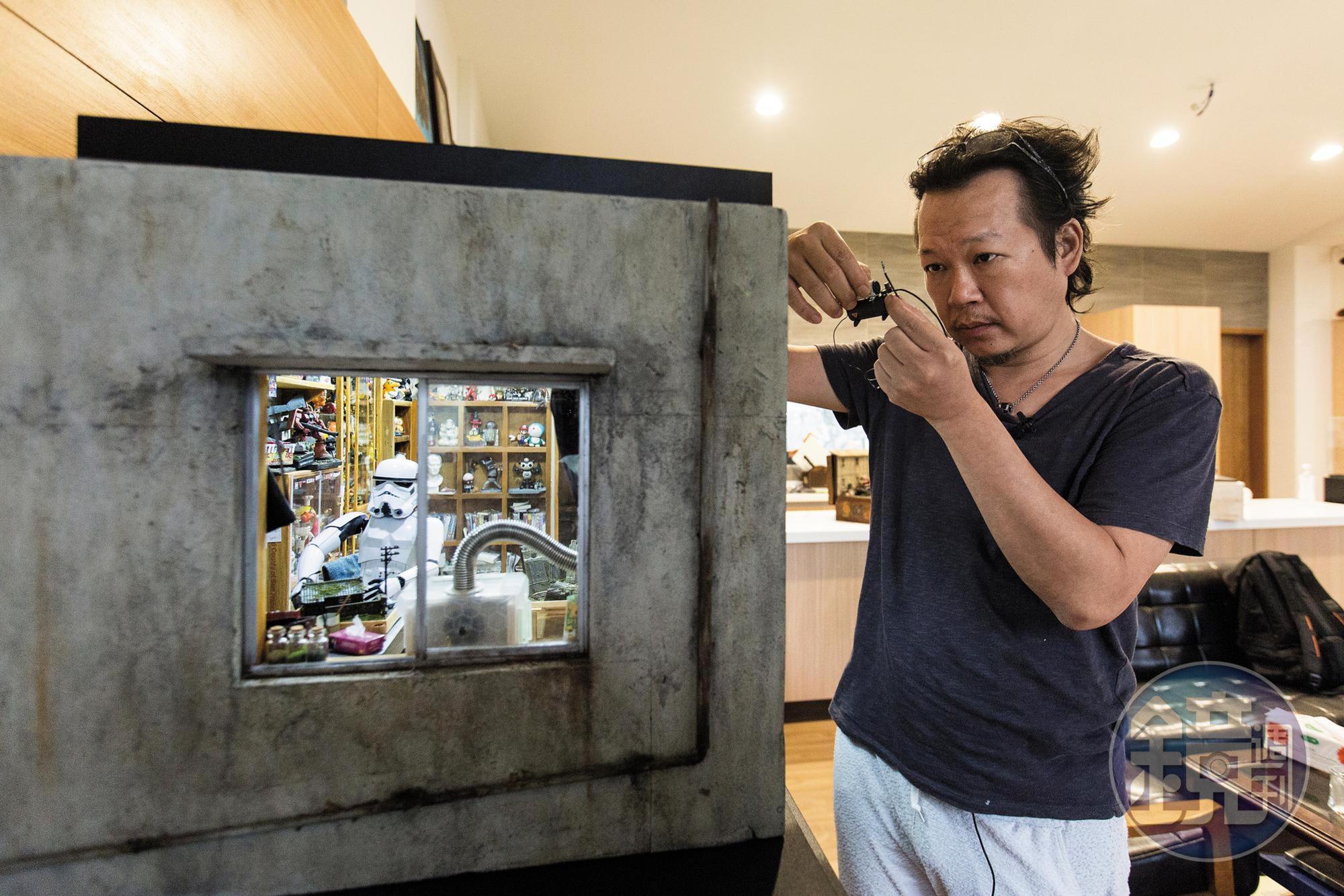 「宅男的房間」作品無實際場景參考，鄭鴻展說，平時靈感來源多來自日常生活及國外畫家的IG、臉書和插畫，他再思考把平面做成微縮模型的可能性。手上所持壓縮機為廢料製作。