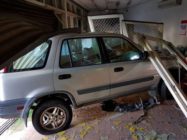 林男駕駛的休旅車卡在小吃店的鐵捲門下。(消防局提供)