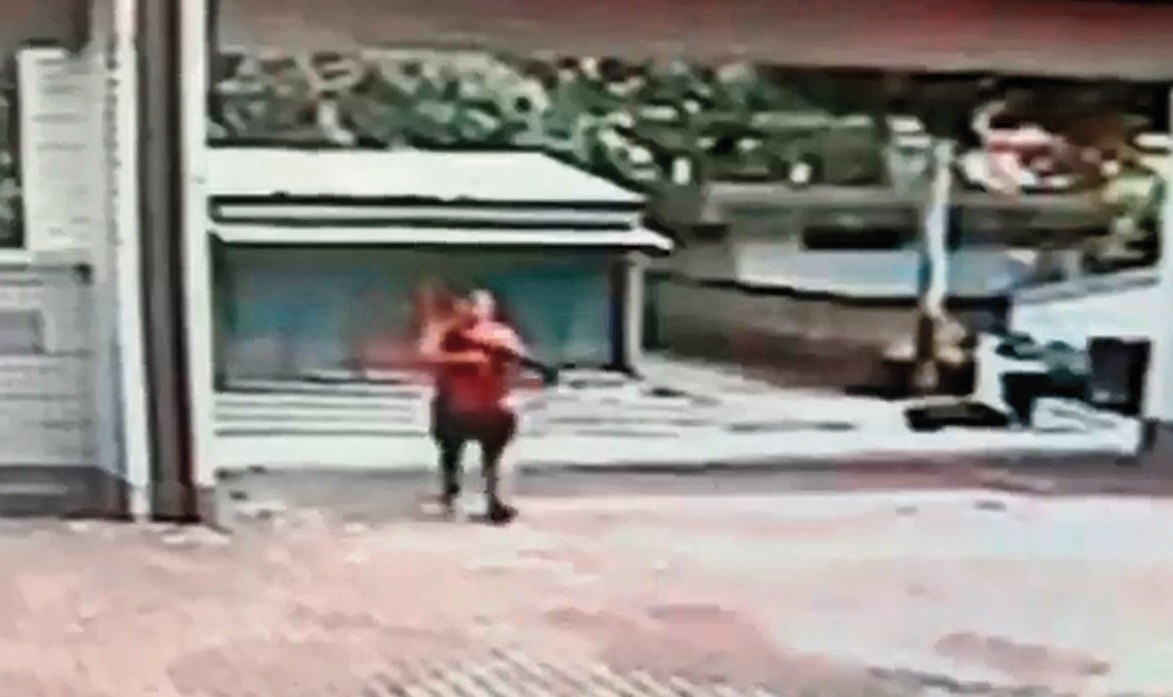 監視器畫面清楚看到江宇倫衝出校門瞄準完中輟生後,手持長槍走回校園。(翻攝畫面)