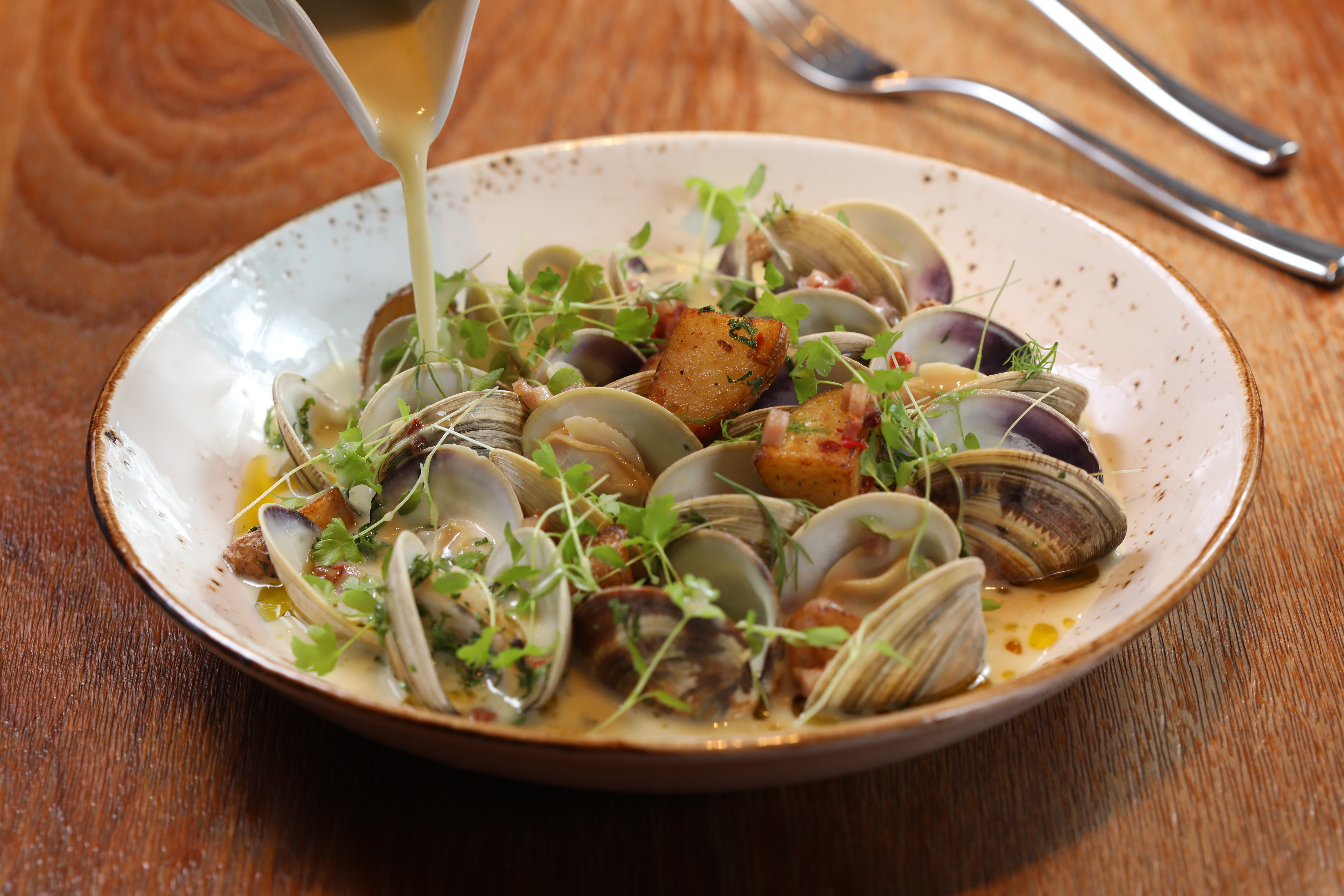「雲林牛奶貝」的奶油高湯以3台斤鮮貝熬煮，點綴上蒔蘿、芹菜，重新詮釋美式蛤蜊巧達湯。（590元／份）