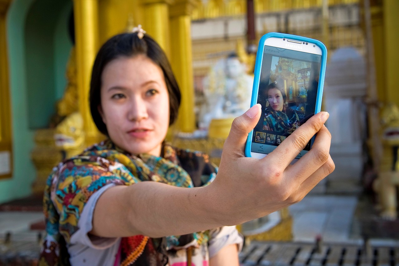 一名女性遊客在緬甸仰光的大金寺外以手機自拍。（東方IC）