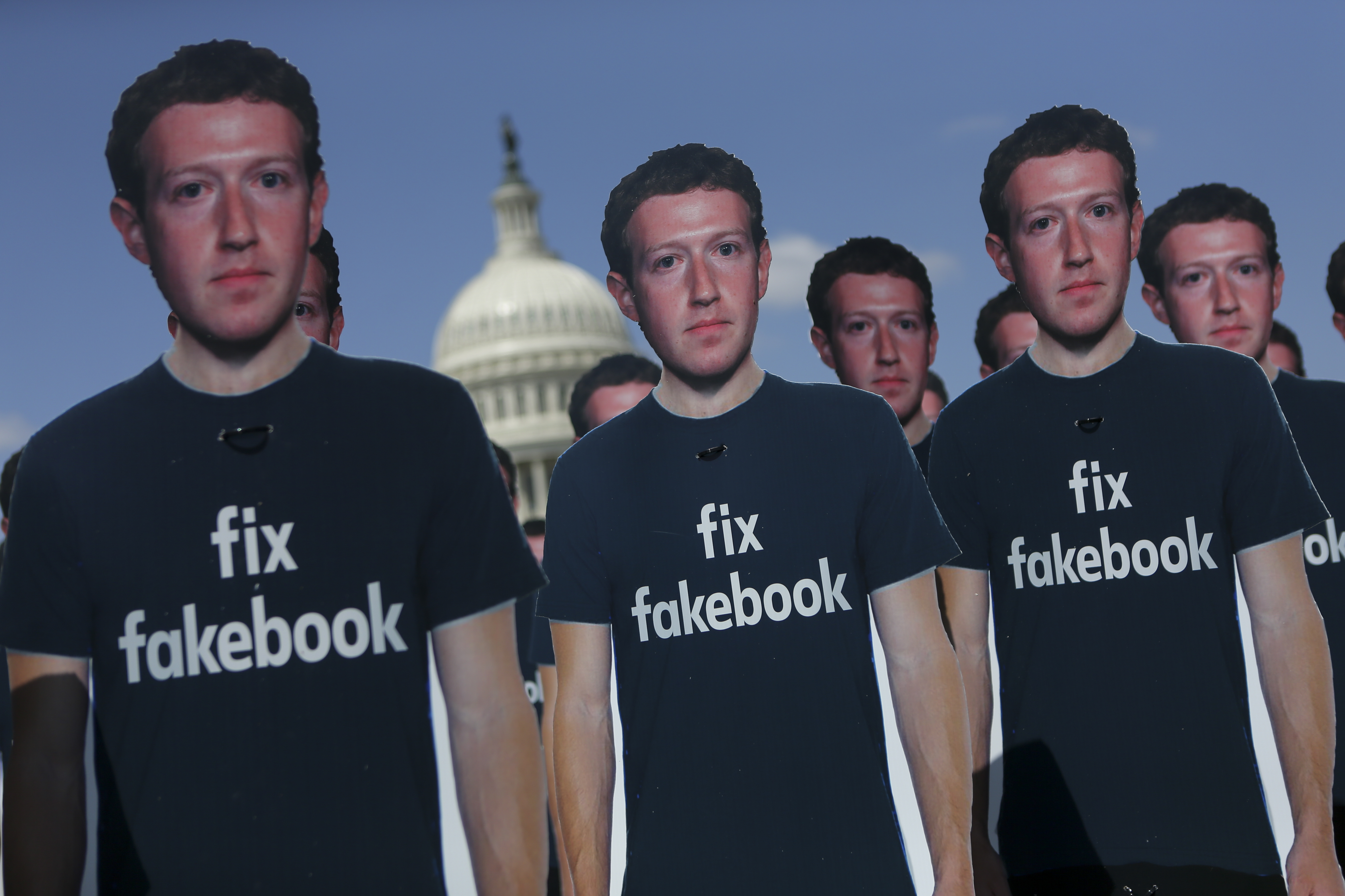 2018年4月10日祖克柏出席美國國會聽證當天,抗議人士在國會草坪擺放100個身穿「修理臉書」T恤的祖克柏人形立牌。(東方IC)