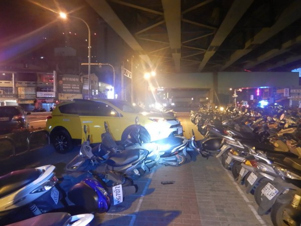 計程車被撞後失控高速衝入陸橋下的機車停車場，7輛機車被撞得面目全非。（警方提供）