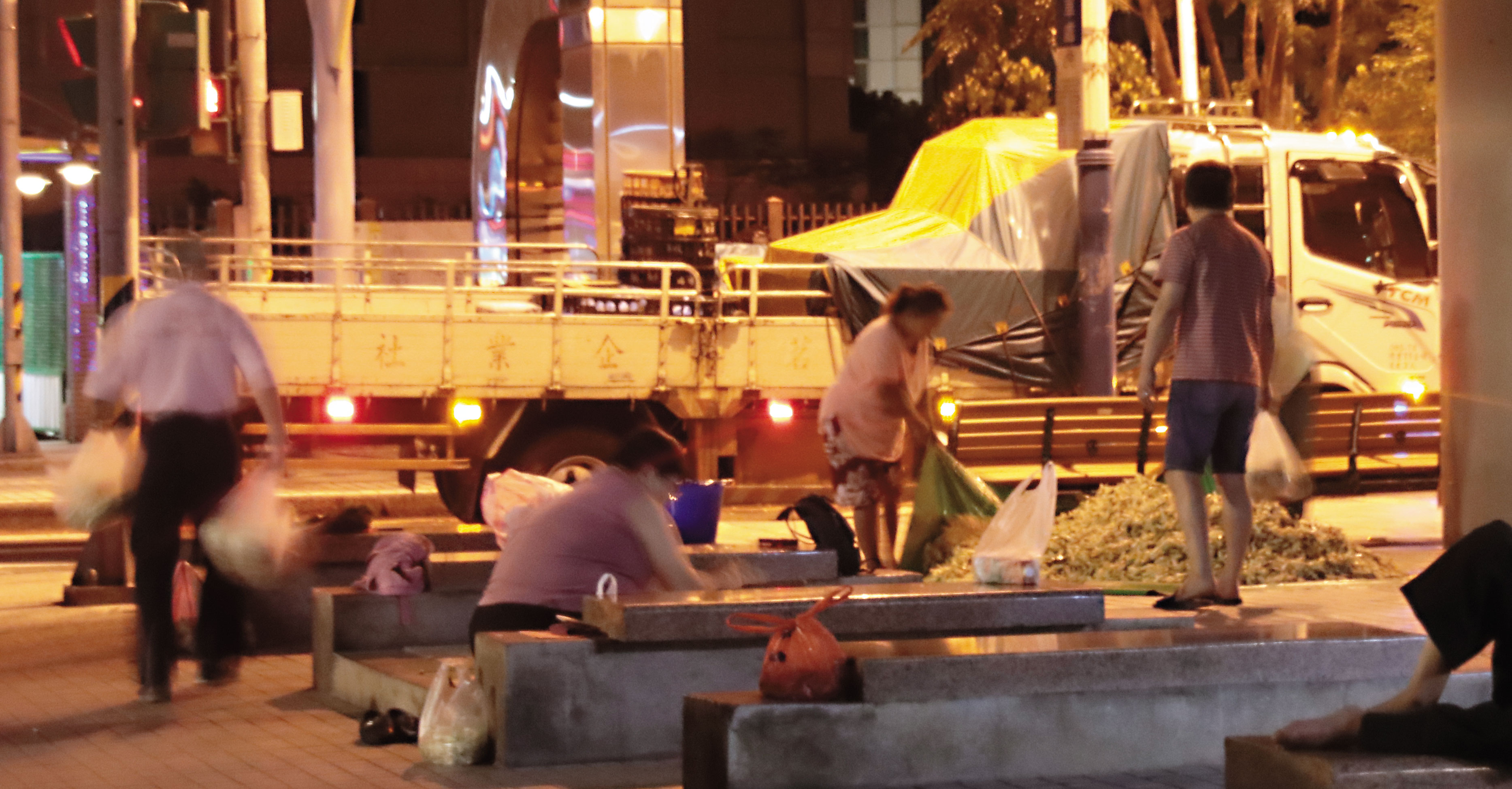 頭帶著夜燈的業者對玉蘭花分裝，即將展開一日的兜售生活。