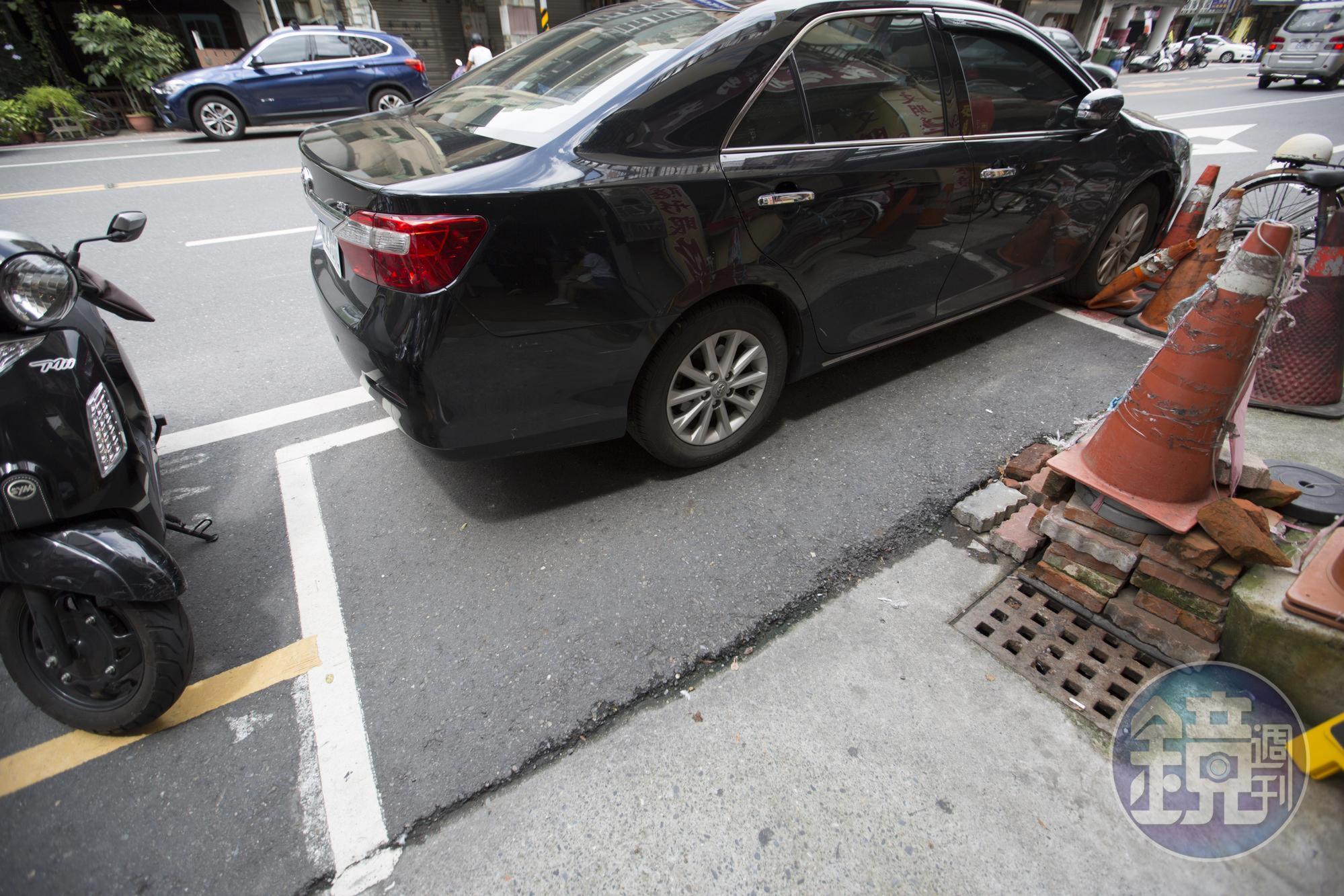 除了停車格長度不夠，轎車車頭無法停在格子裡，路旁還有居民推放的三角錐等障礙物。