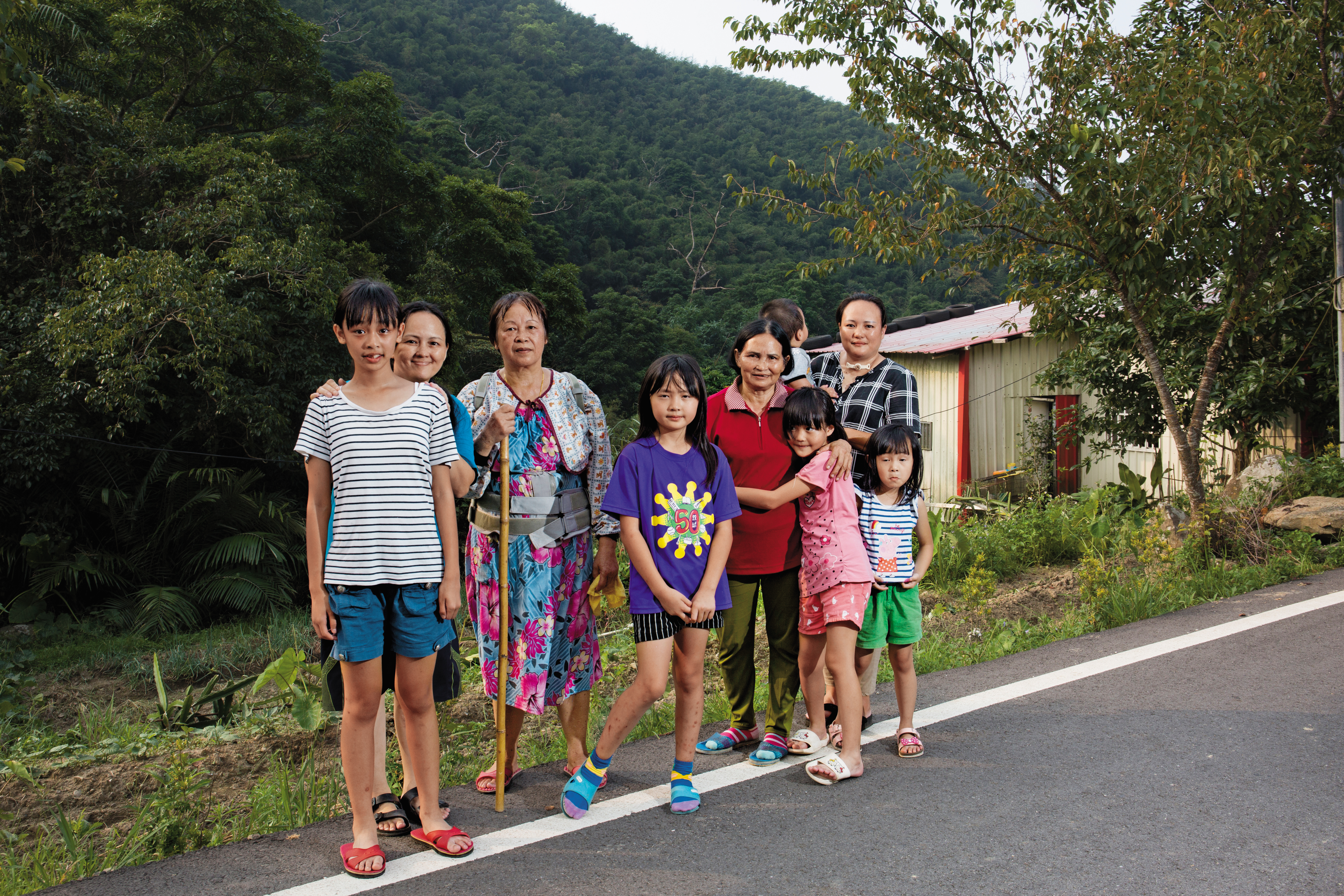 邱雅詩（中）、邱雅霓（右3）姊妹平時由姑姑、奶奶照顧，右後方的鐵皮屋就是她們的家。