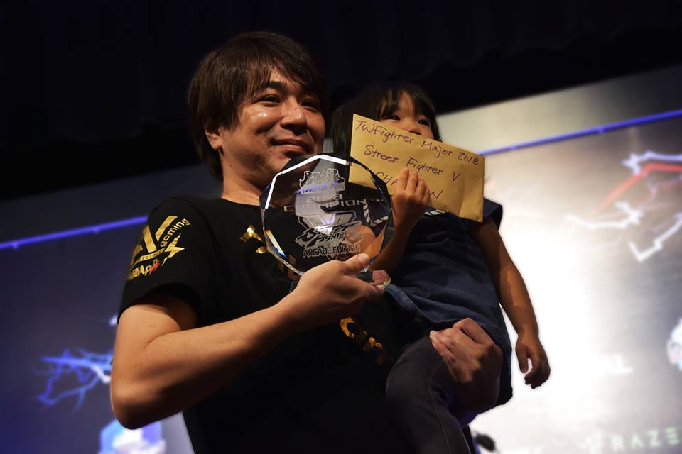 Sako在「鬪魂2018」奪下《快打旋風5-大型電玩版》冠軍，賽後開心與女兒合照。（圖：翻攝自TWFighter 台灣格鬥遊戲社群官方臉書）