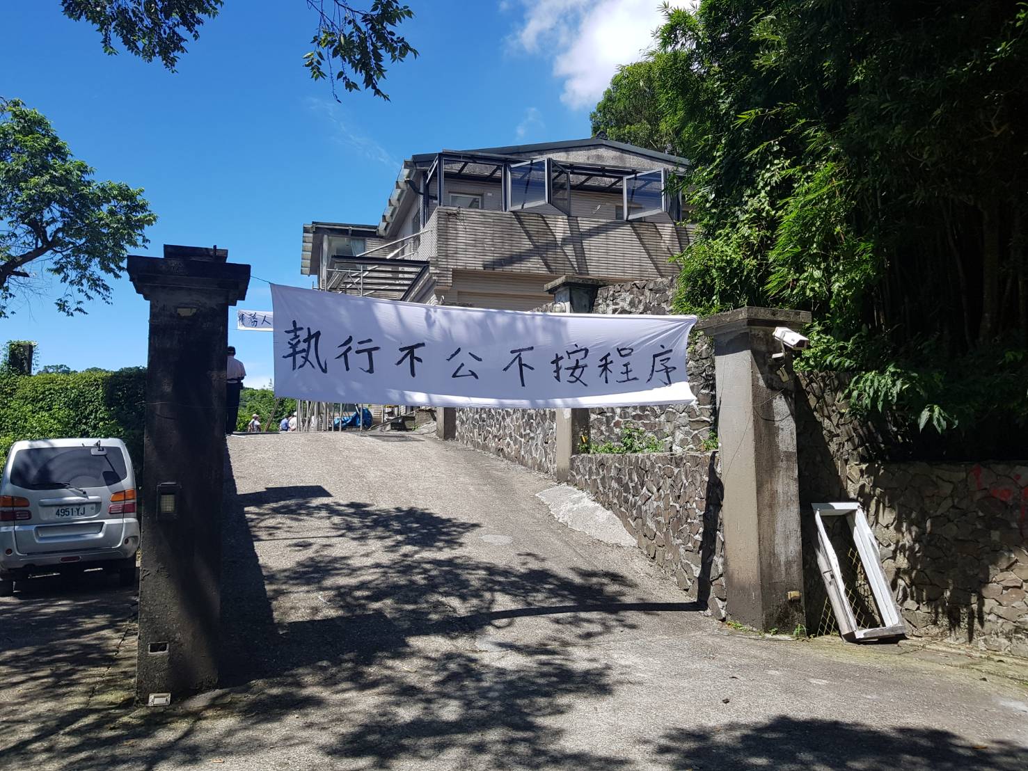 屋主質疑拆屋程序有瑕疵,拉起白布條抗議。