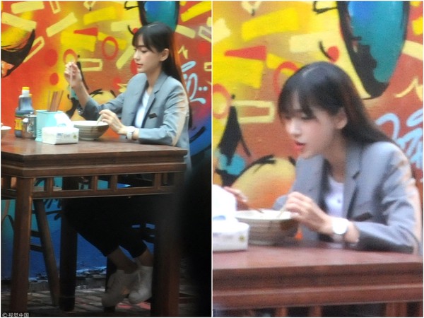 Angelababy流著妹妹頭,穿著灰色西裝外套配白T恤、九分褲,率性坐在路邊小吃攤大口吃麵。(翻攝自微博)