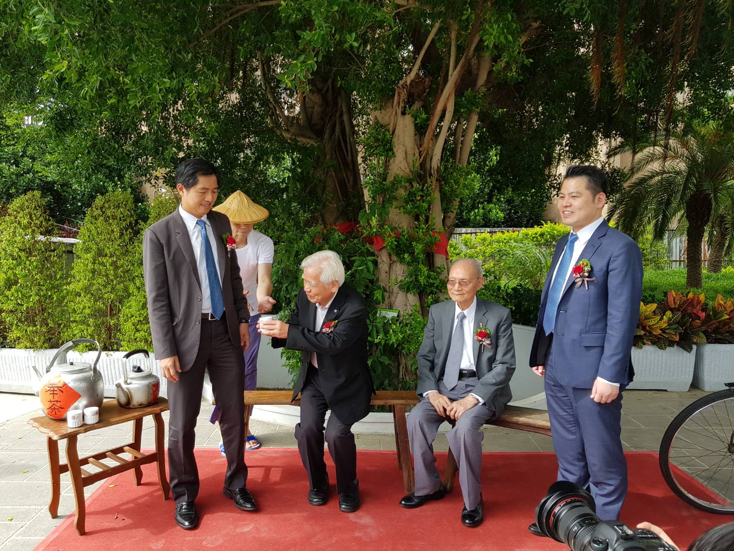 長虹建設董事長李文造（左二）率領二個兒子，長虹建設總經理李耀中（左）與長虹建設副總經理李耀民（右）與忠孝詠吉的大地主、啟台公司董事長蔡永興（右二），在樹齡117年的榕樹下接受奉茶儀式。