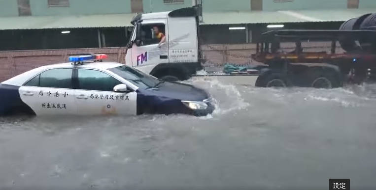 警車受困水中，大卡車一經過，水壓讓警車在水中飄移。（翻攝自爆料公社）