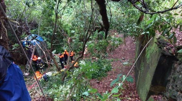 小貨車墜落山谷嚴重扭曲變形,消防員攀繩進入陡峭的山溝搶救,但夫妻倆最後都已身亡。(消防局提供)